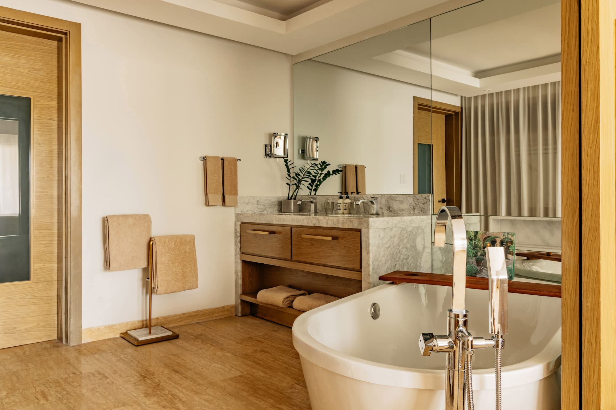 Modern bathroom with freestanding tub, marble vanity, and warm wood accents.