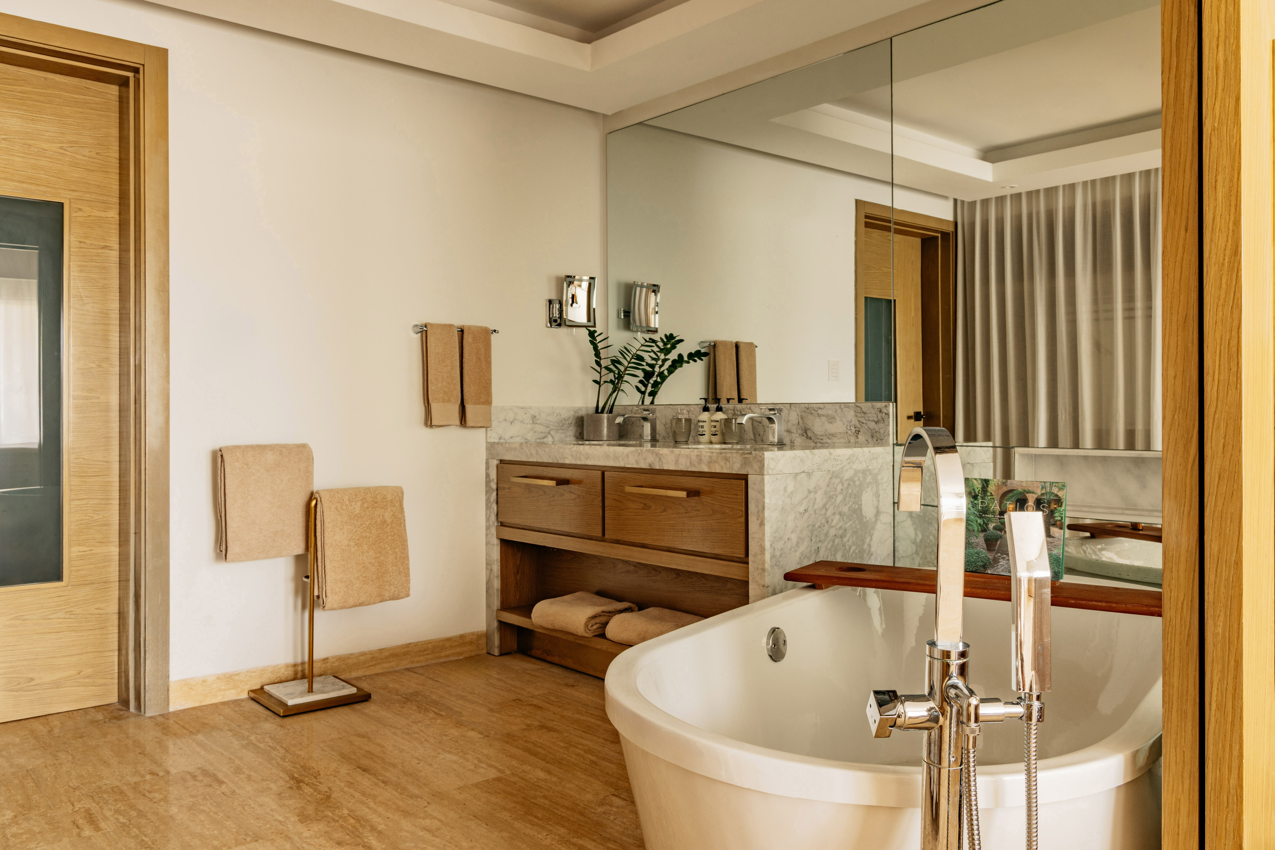 Modern bathroom with freestanding tub, marble vanity, and warm wood accents.