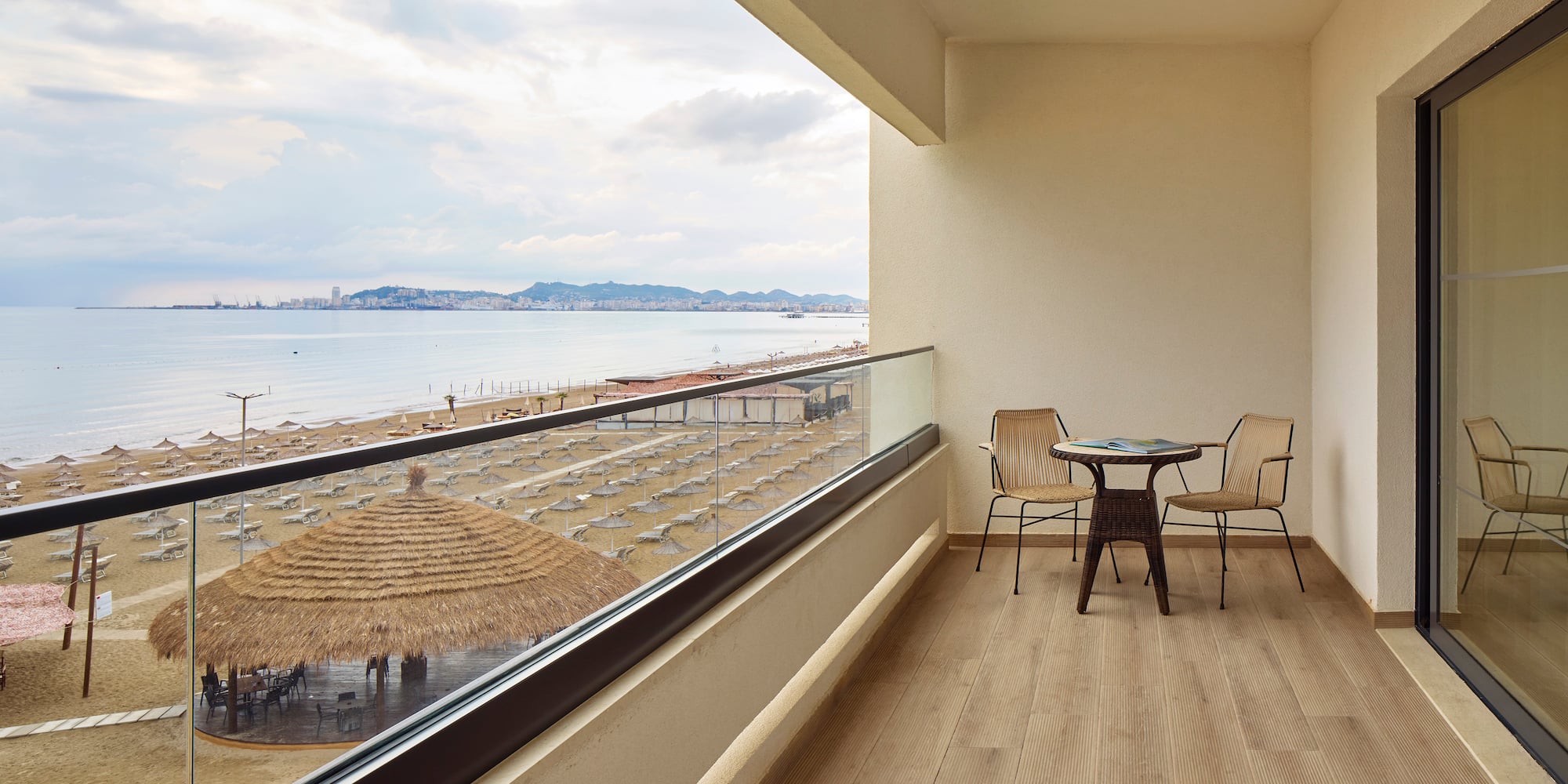 a balcony with chairs and a table overlooking a beach
