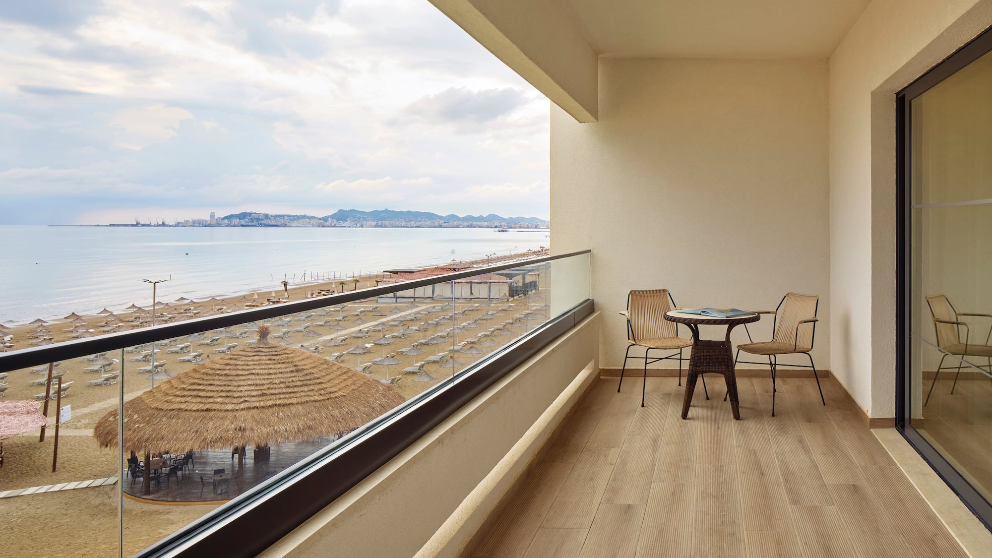 a balcony with chairs and a table overlooking a beach