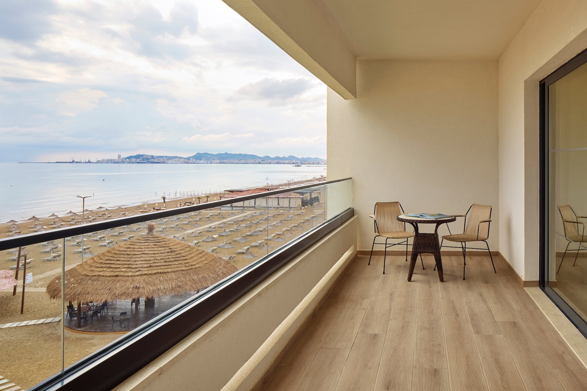 a balcony with chairs and a table overlooking a beach