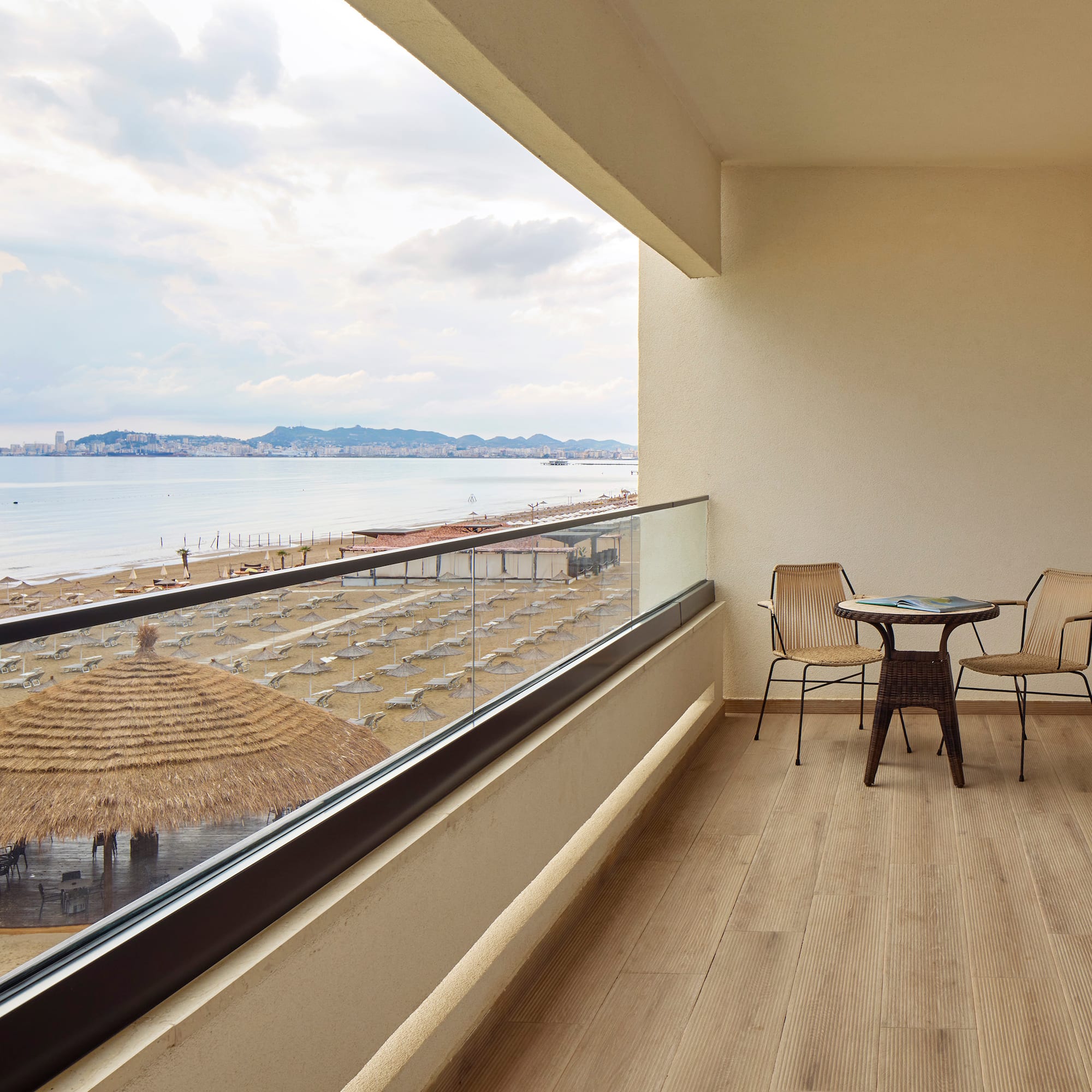 a balcony with chairs and a table overlooking a beach