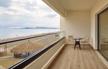 a balcony with chairs and a table overlooking a beach