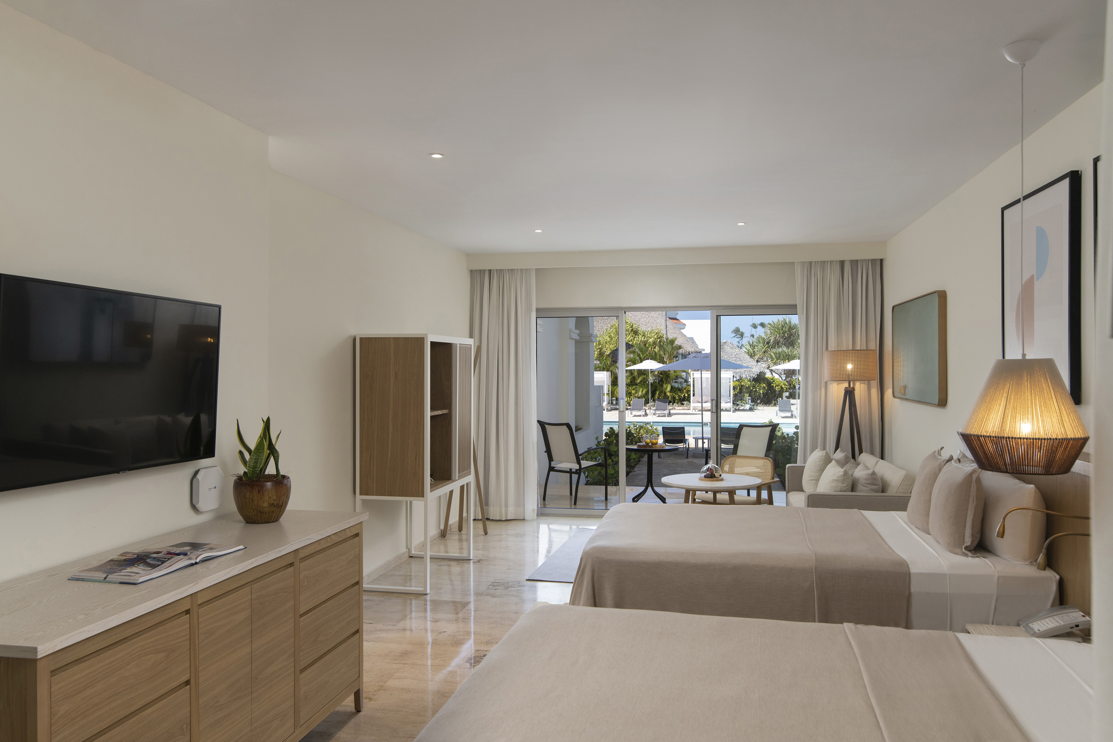 Spacious hotel room with two beds, pool view, and private balcony.