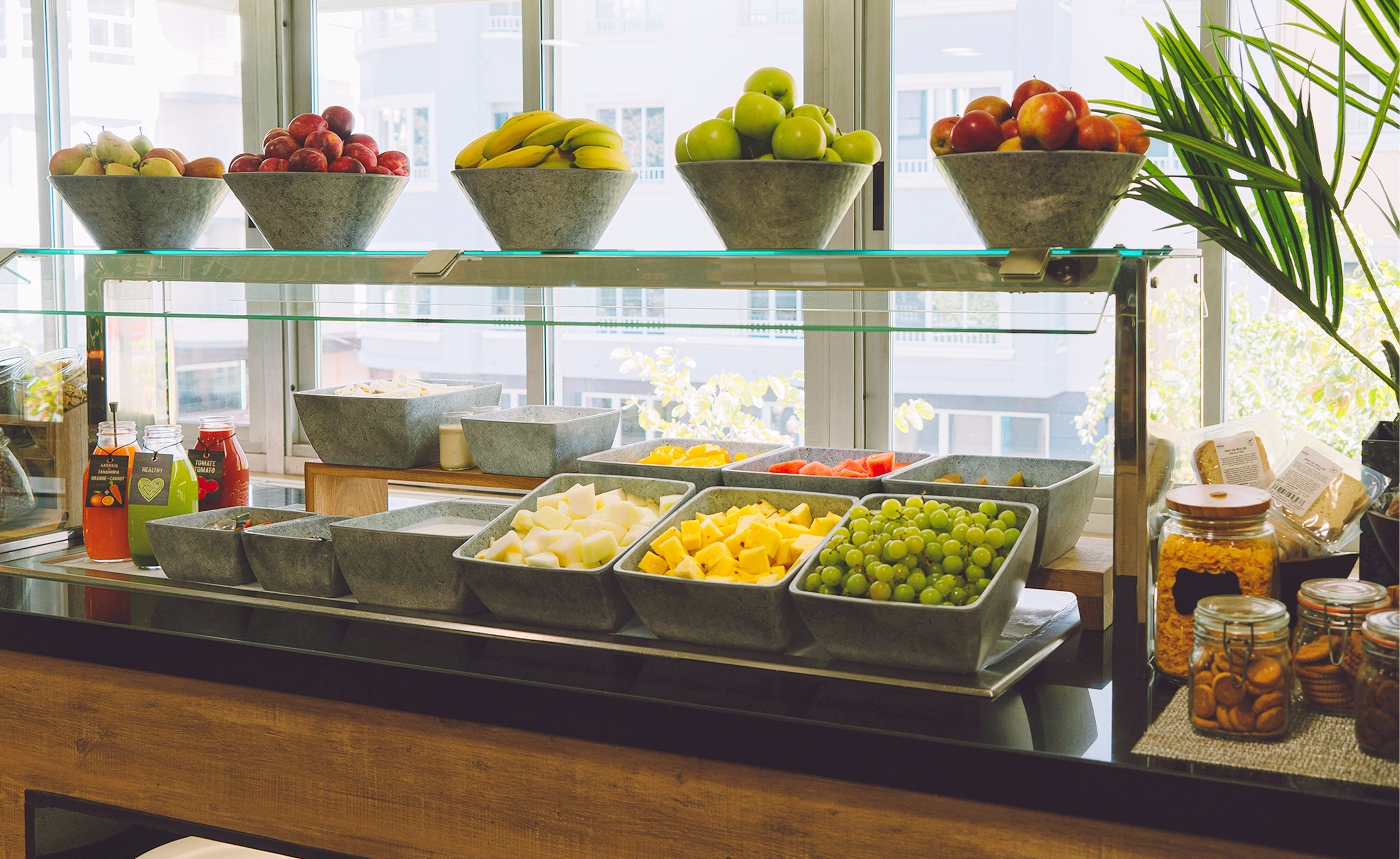 Fruit bar buffet with fresh whole and diced fruits, juices, and cereals.