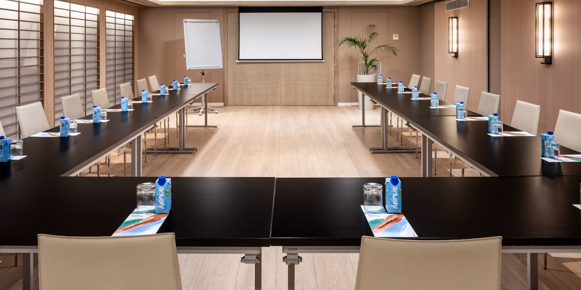 a room with a large screen and tables