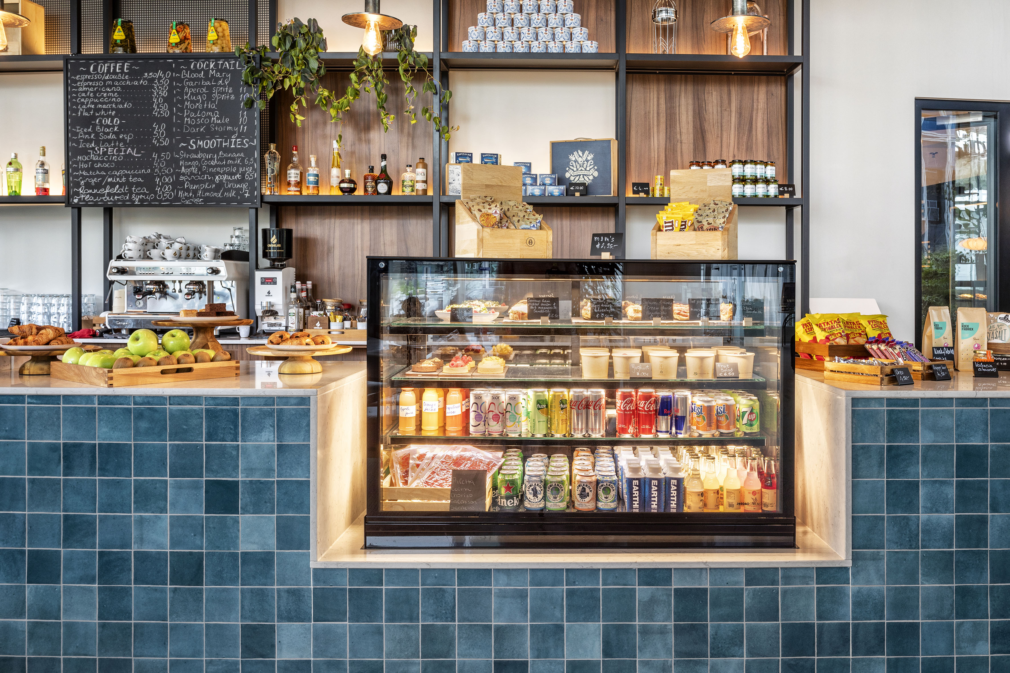 Modern cafe counter with food and drink display, coffee machine, and menu.