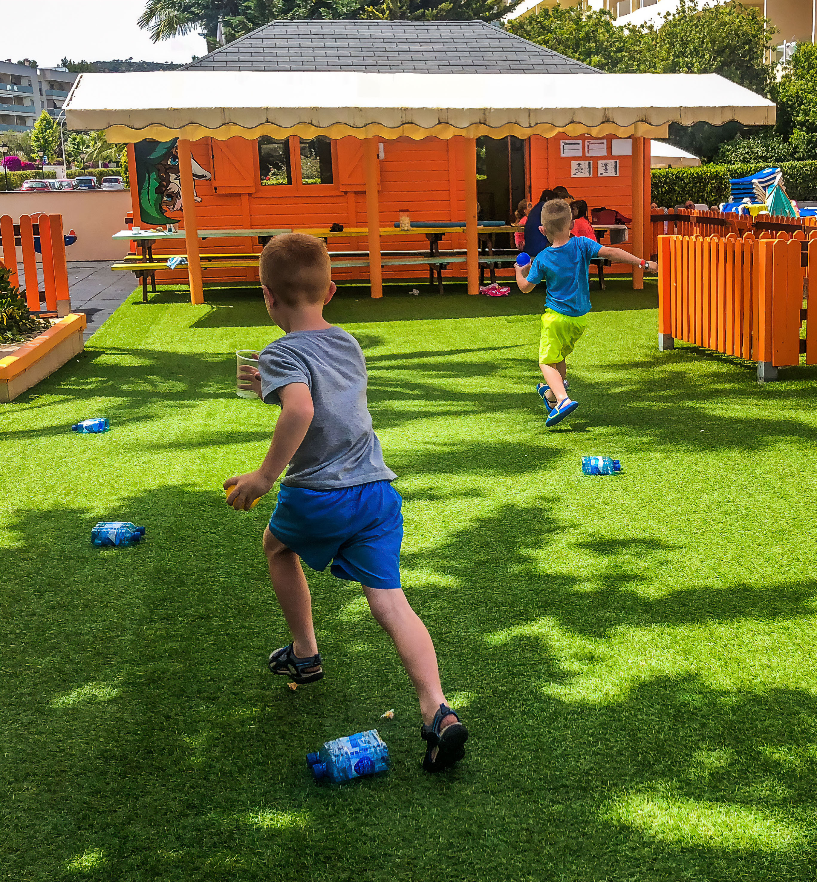 Two boys running on artificial turf in a vibrant outdoor kids' play area.