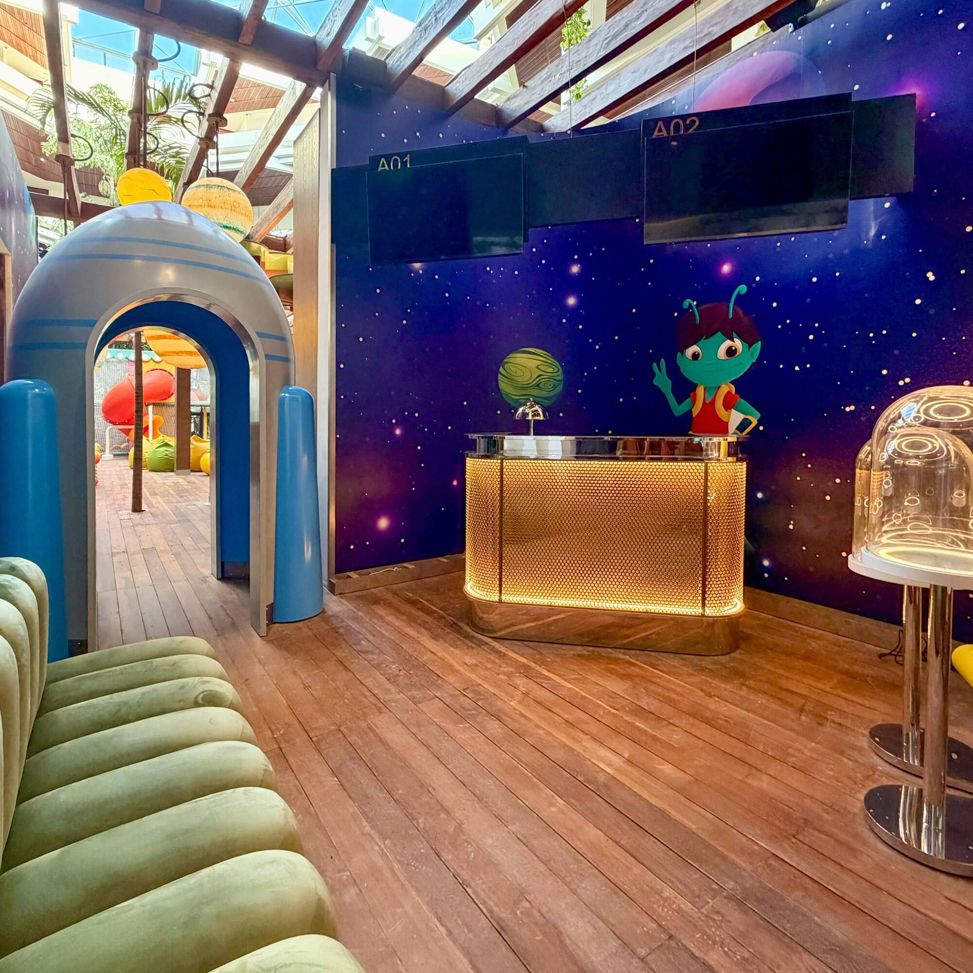 Kids' space play zone with rocket entry, alien art, and glowing reception desk.
