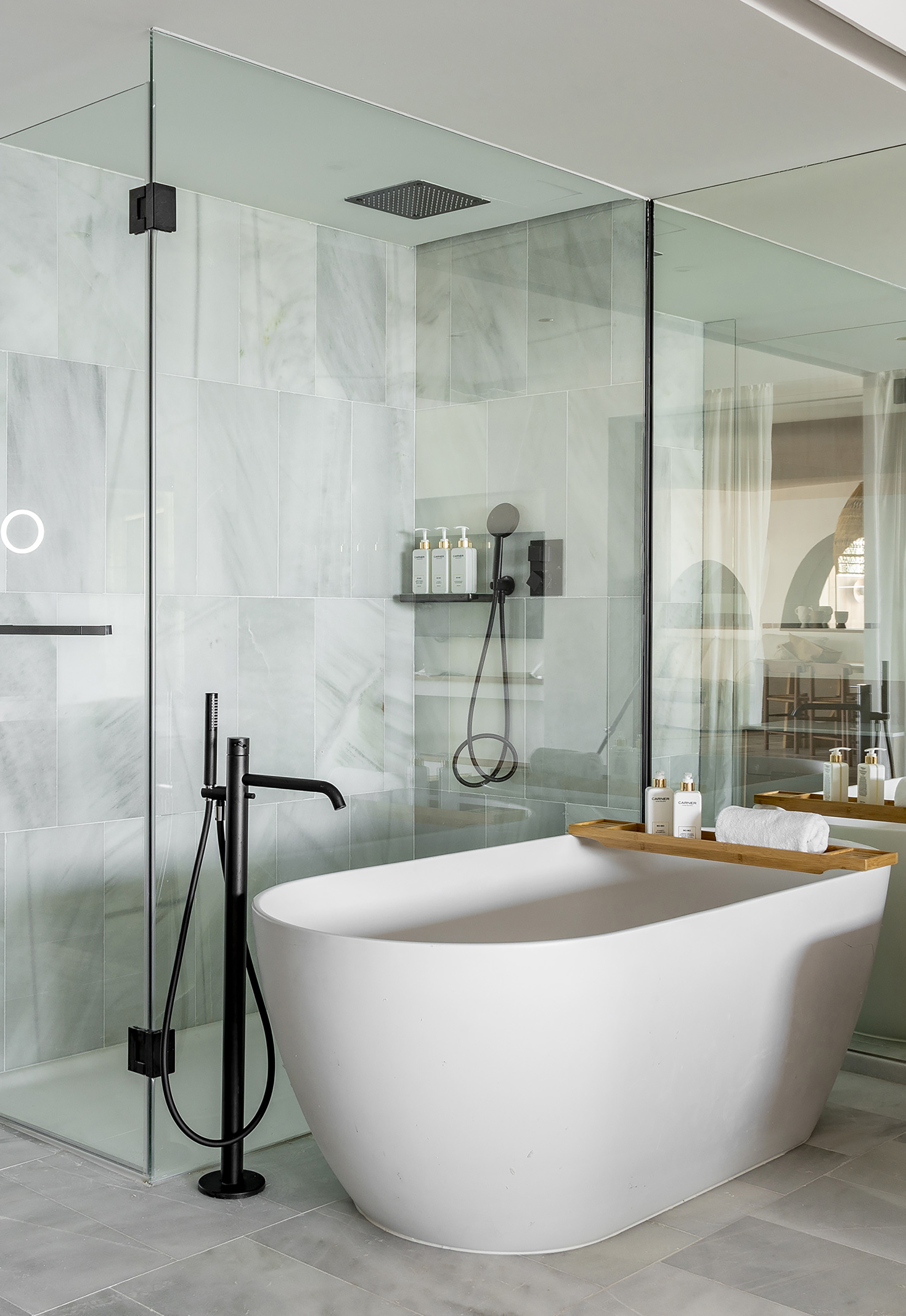 Sleek bathroom with white freestanding tub, glass shower, and black matte fixtures.