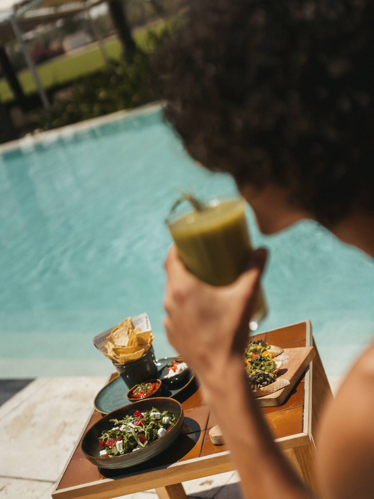 a person holding a drink by a pool