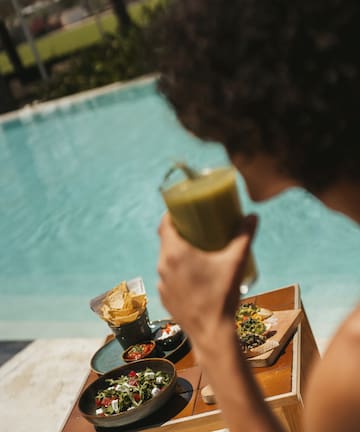 a person holding a drink by a pool