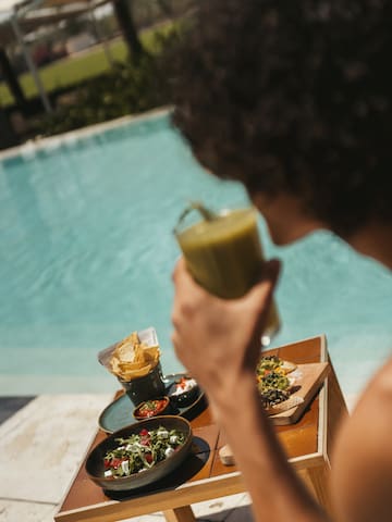 a person holding a drink by a pool