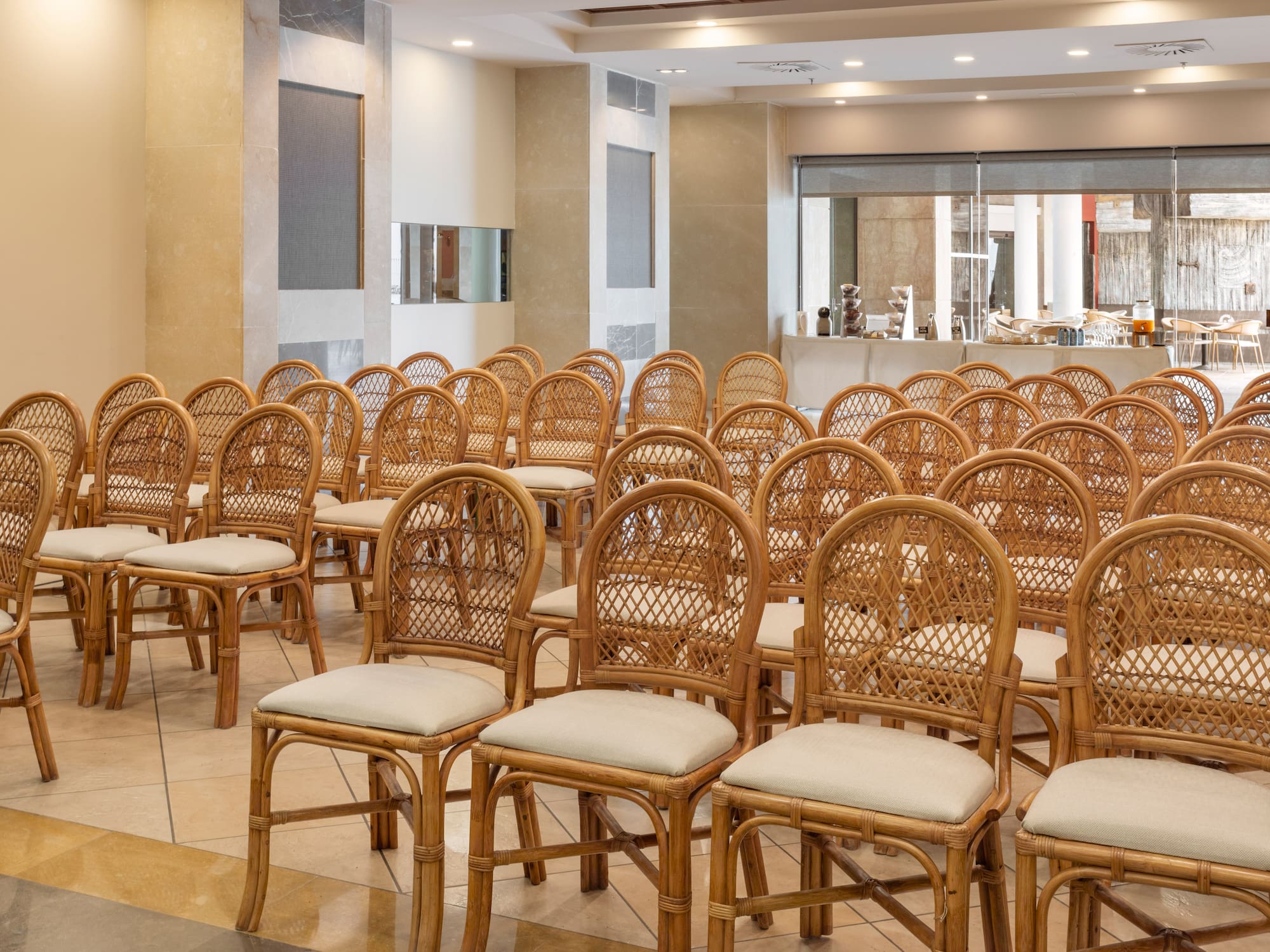 Rattan chairs with light cushions in conference room or event venue.