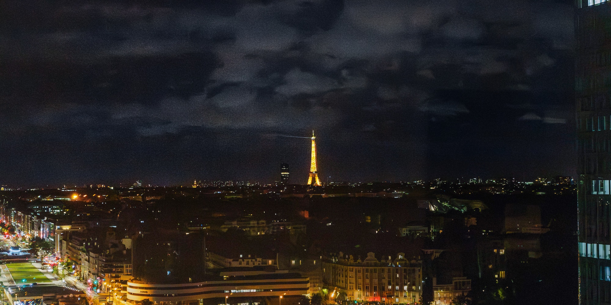 Illuminated Eiffel Tower overlooking Paris city skyline at night.