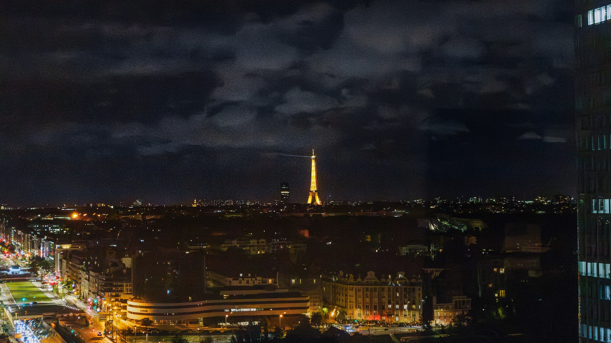 Illuminated Eiffel Tower overlooking Paris city skyline at night.