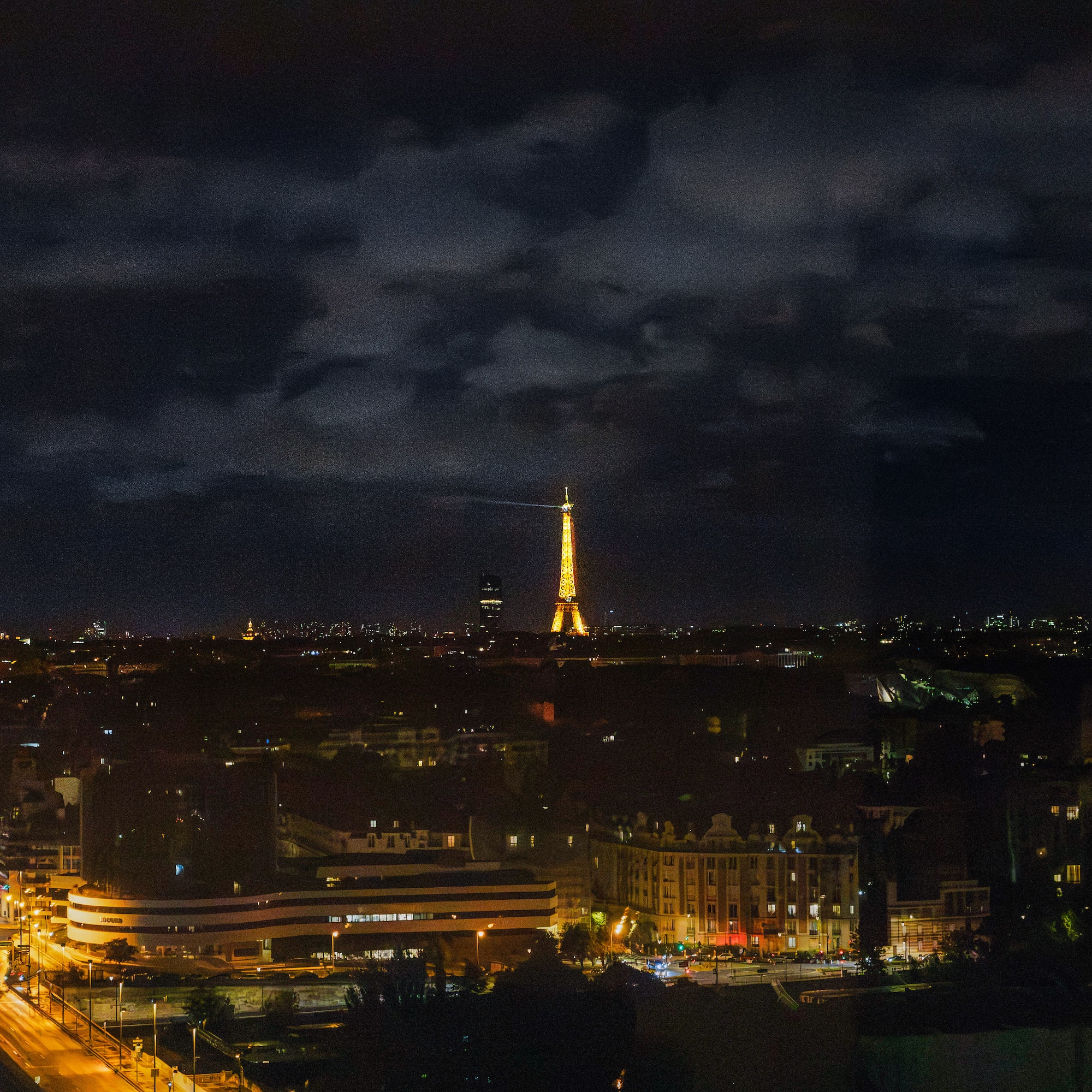 Illuminated Eiffel Tower overlooking Paris city skyline at night.