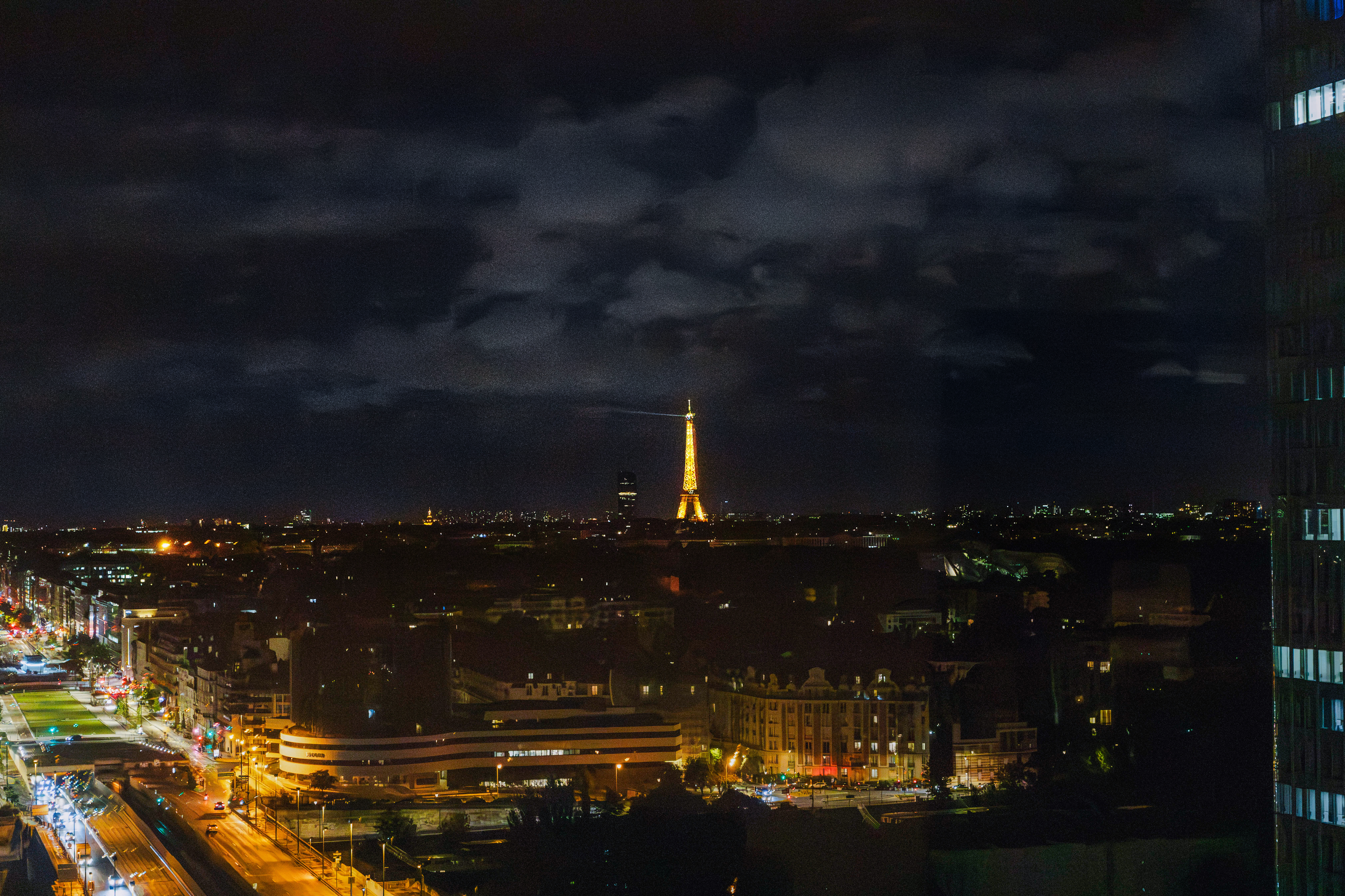 Illuminated Eiffel Tower overlooking Paris city skyline at night.