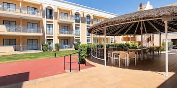 a patio with a thatched roof and chairs