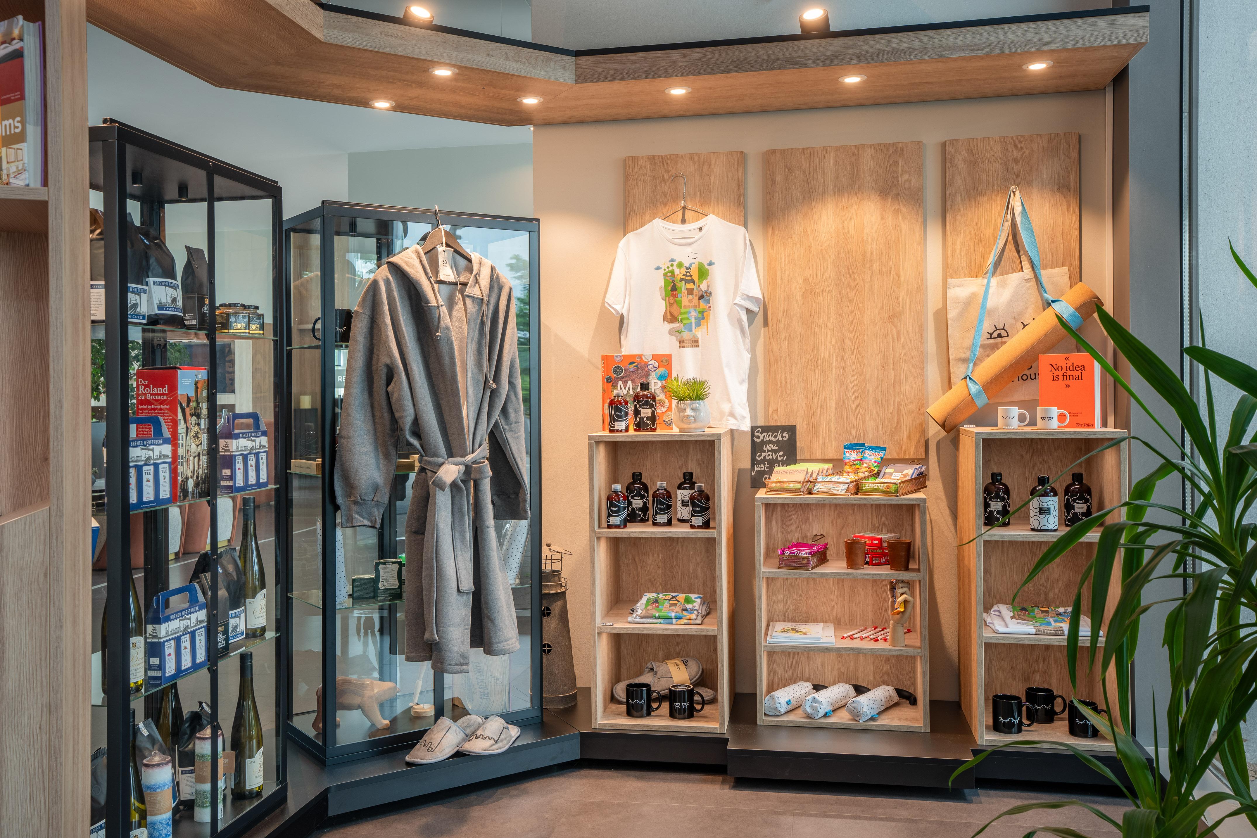 Bremen hotel shop display: bathrobe, t-shirt, snacks, mugs, and local souvenirs.