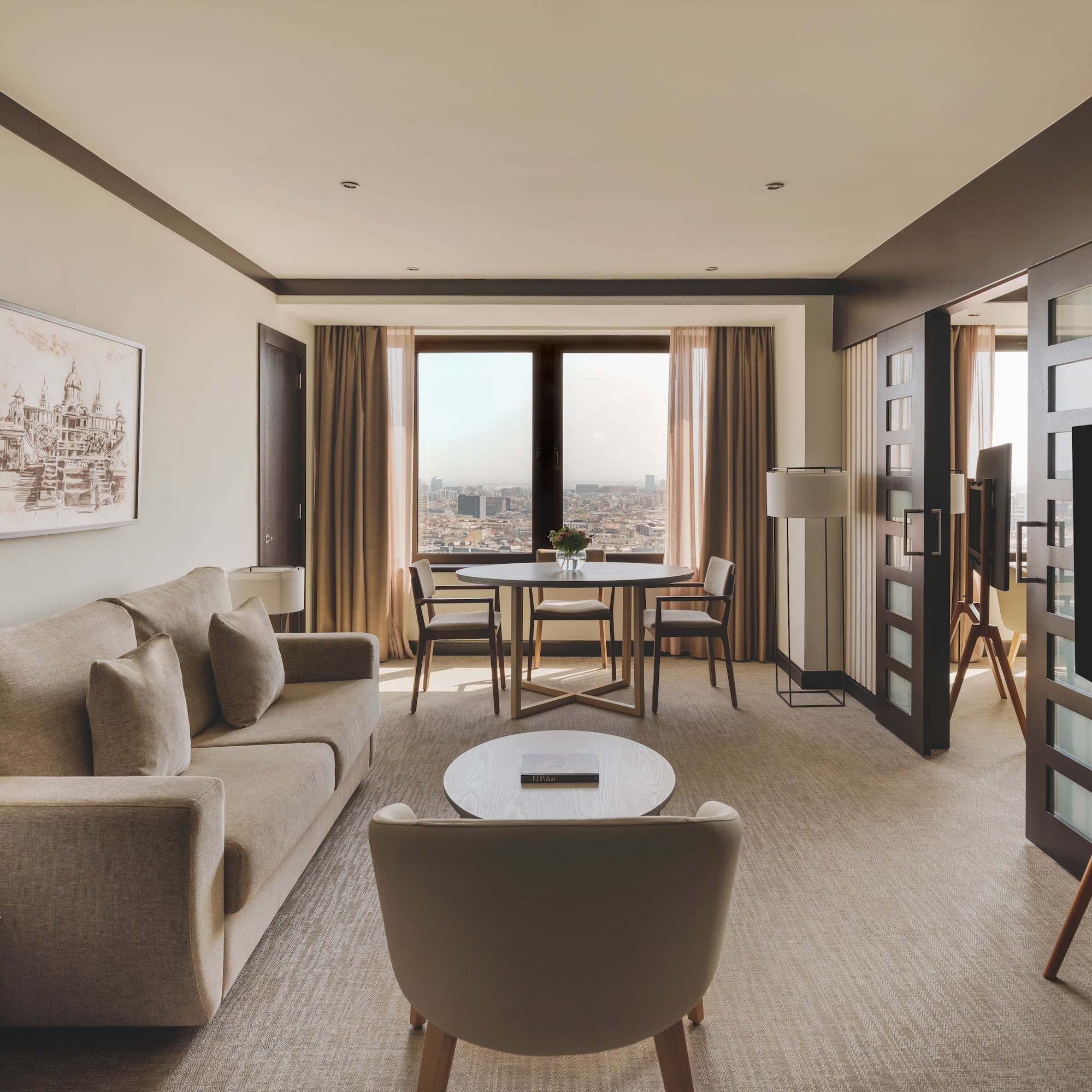 Suite de lujo con sala, sofá, mesa de comedor y vistas panorámicas a la ciudad.