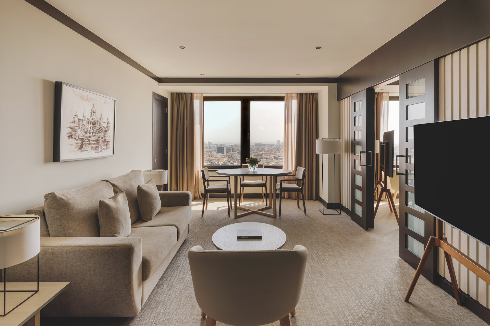 Suite de lujo con sala, sofá, mesa de comedor y vistas panorámicas a la ciudad.