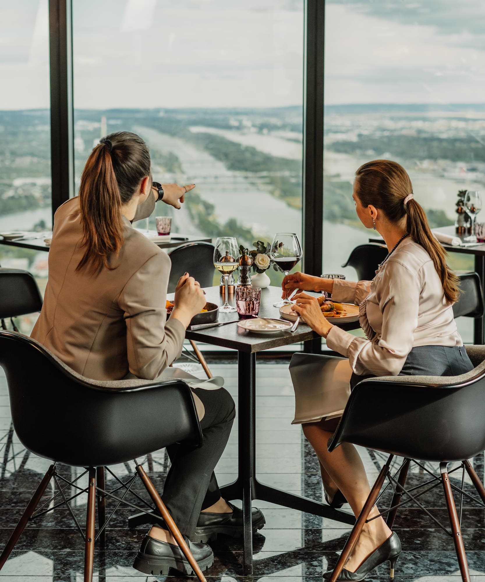 a group of women sitting at a table with a view of a river and a city