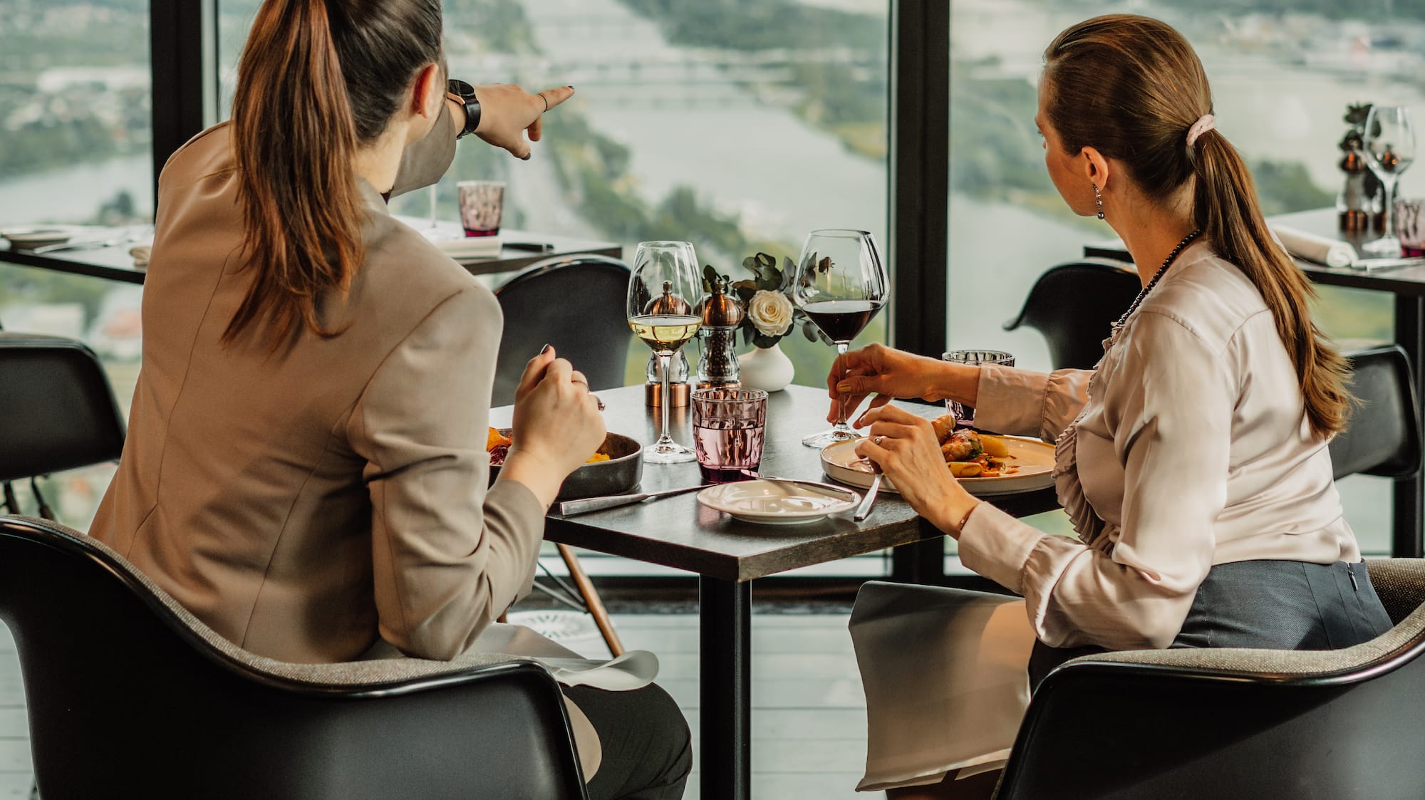 a group of women sitting at a table with a view of a river and a city