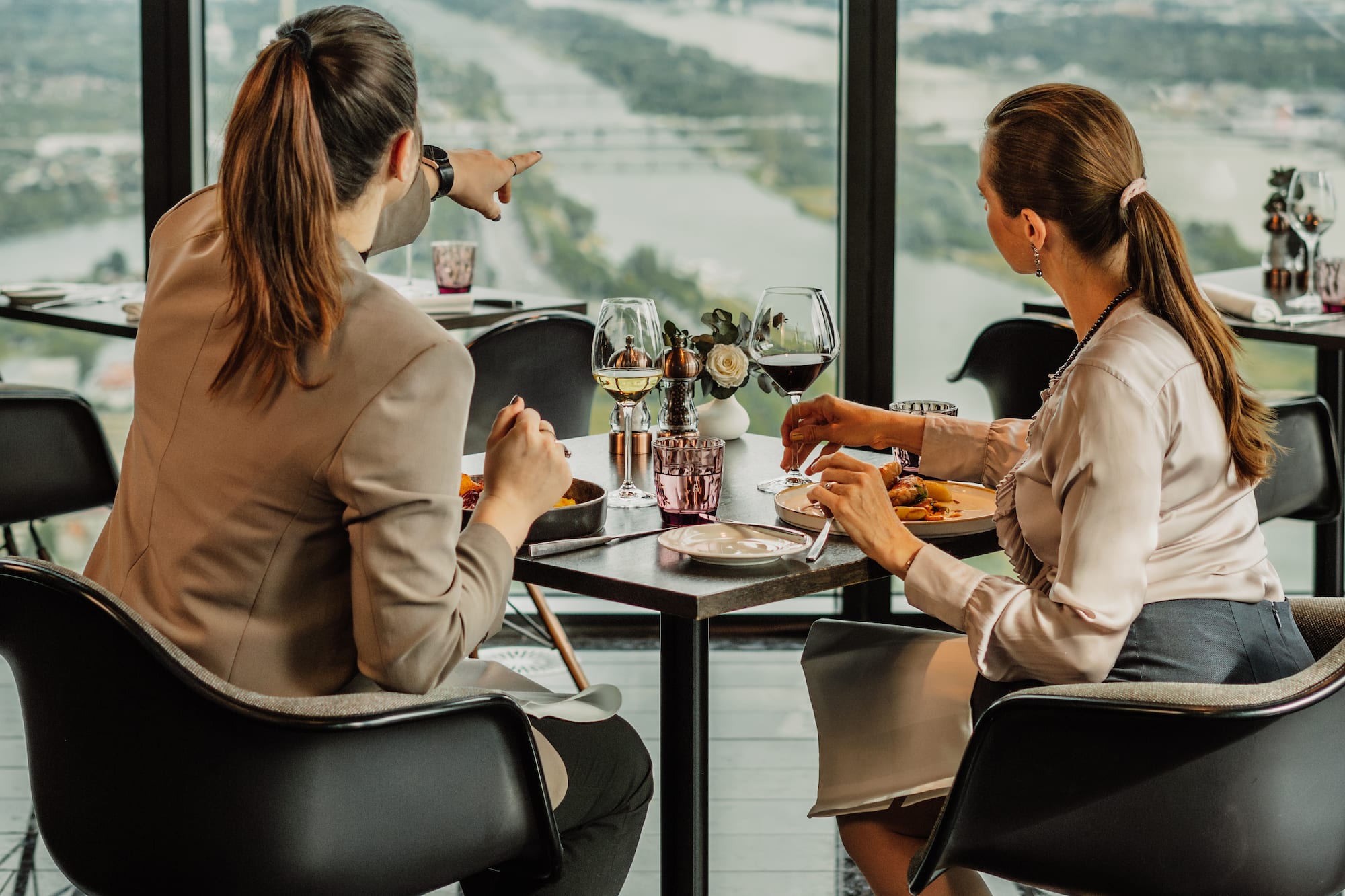 a group of women sitting at a table with a view of a river and a city