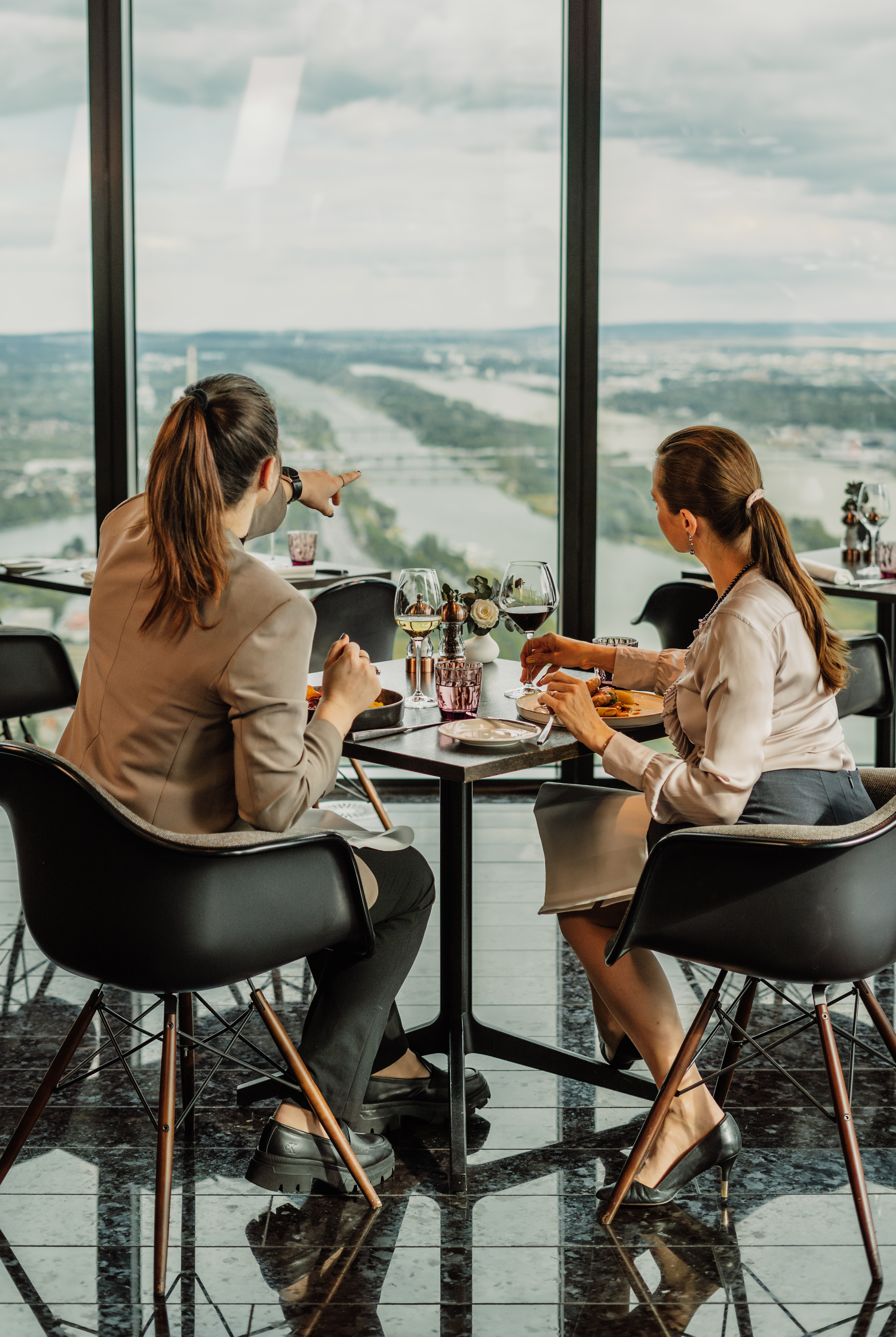 a group of women sitting at a table with a view of a river and a city
