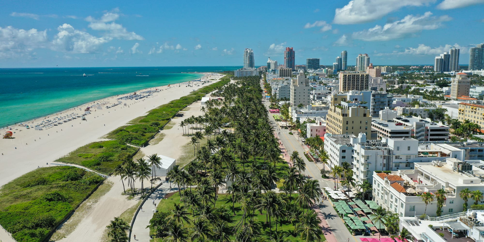 Vista aérea Miami Beach: rascacielos, palmeras, playa y océano turquesa.