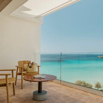 a balcony with a table and chairs and a beach view