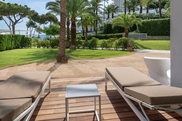 a deck with chairs and tables in front of a palm tree