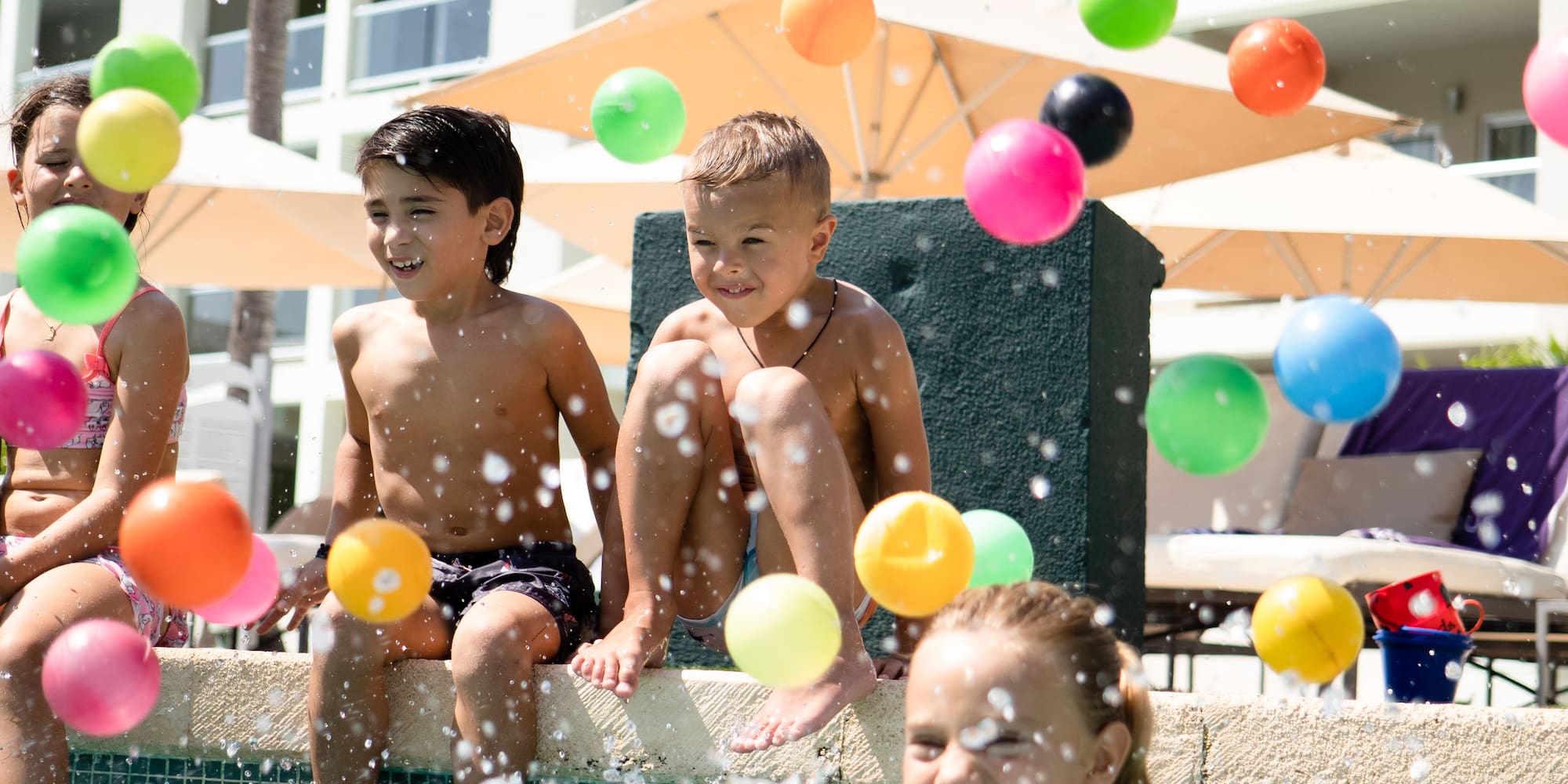 a group of kids playing with balls in a pool