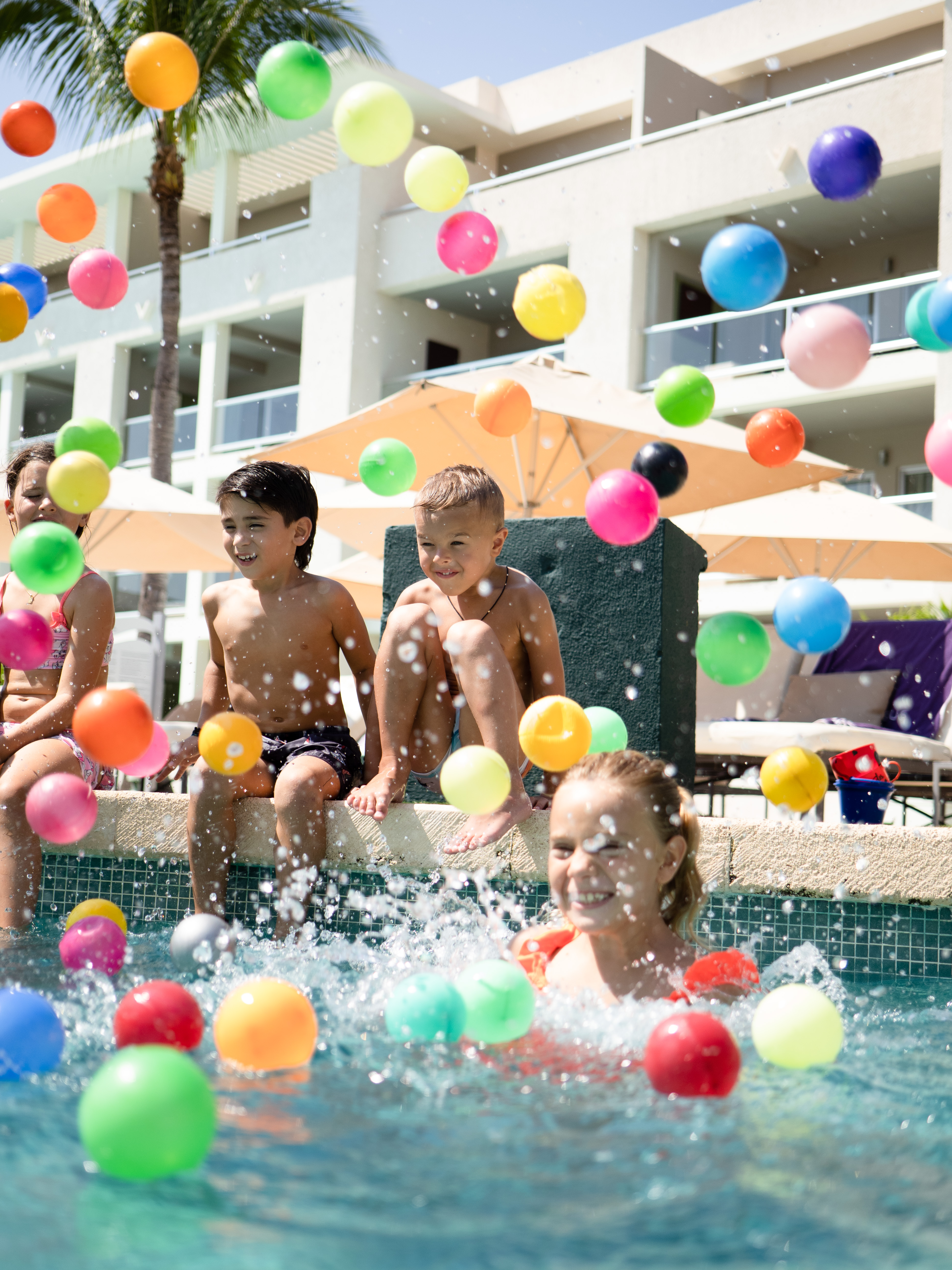 a group of kids playing with balls in a pool
