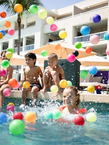 a group of kids playing with balls in a pool