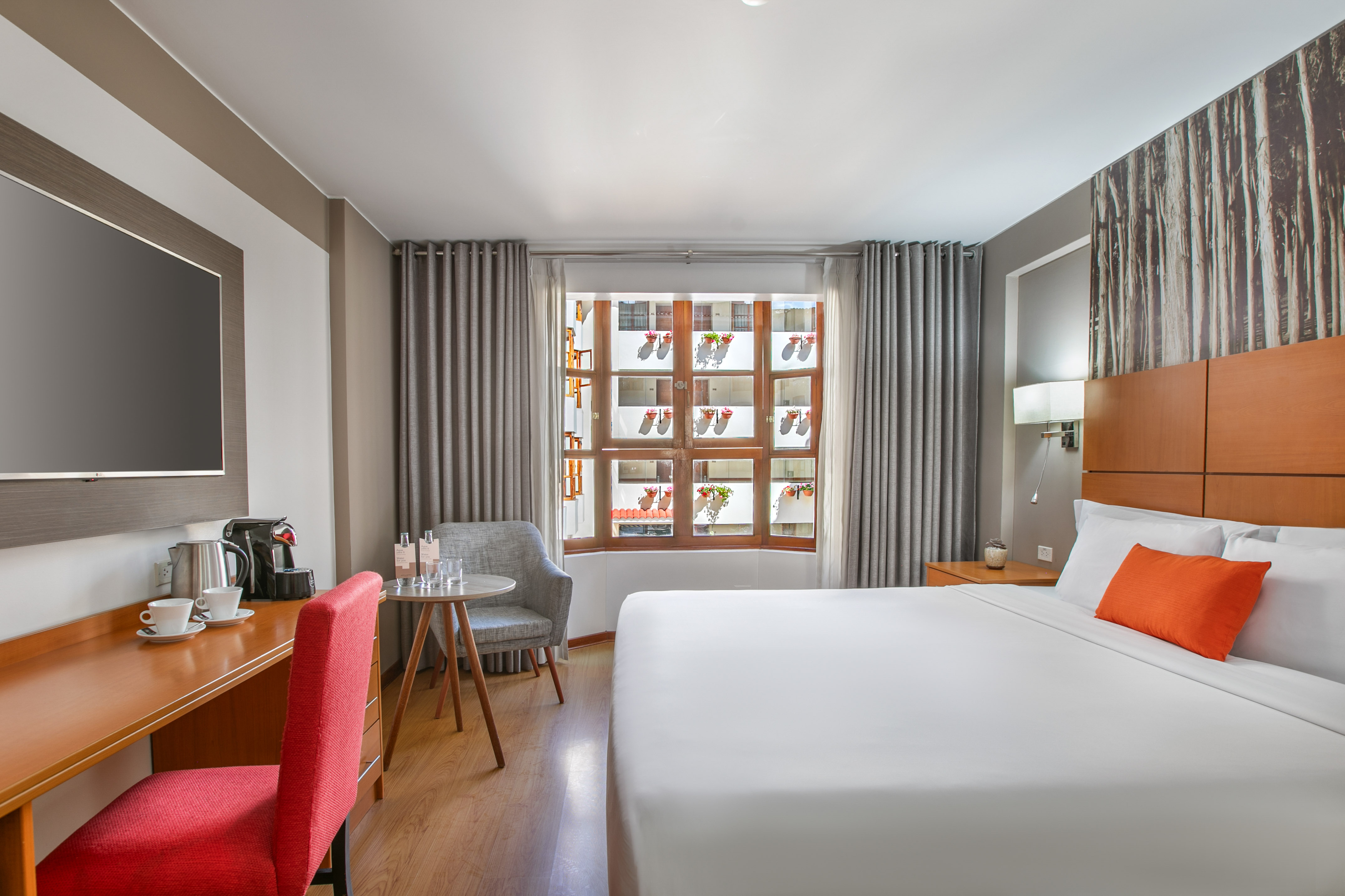 Modern hotel room with a large bed, TV, desk, and a window with curtains. - Hotel Cusco La Paccha Affiliated by Meliá, Cusco