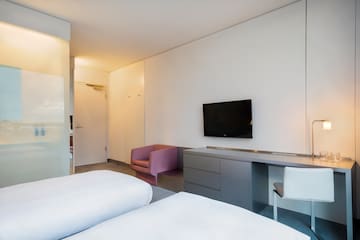 a room with two beds and a tv on the wall