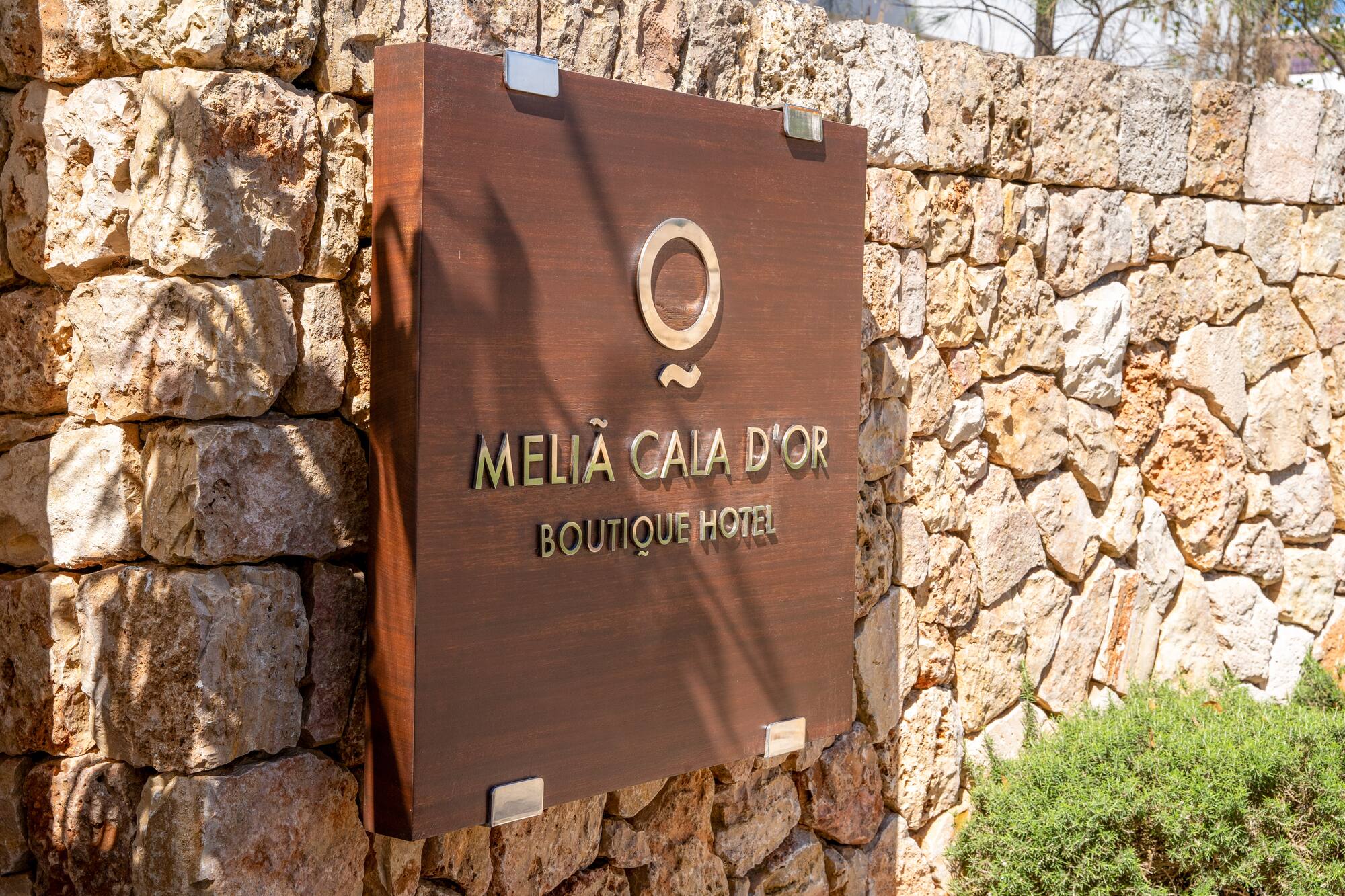 Meliá Cala d'Or Boutique Hotel sign on a rustic stone wall.