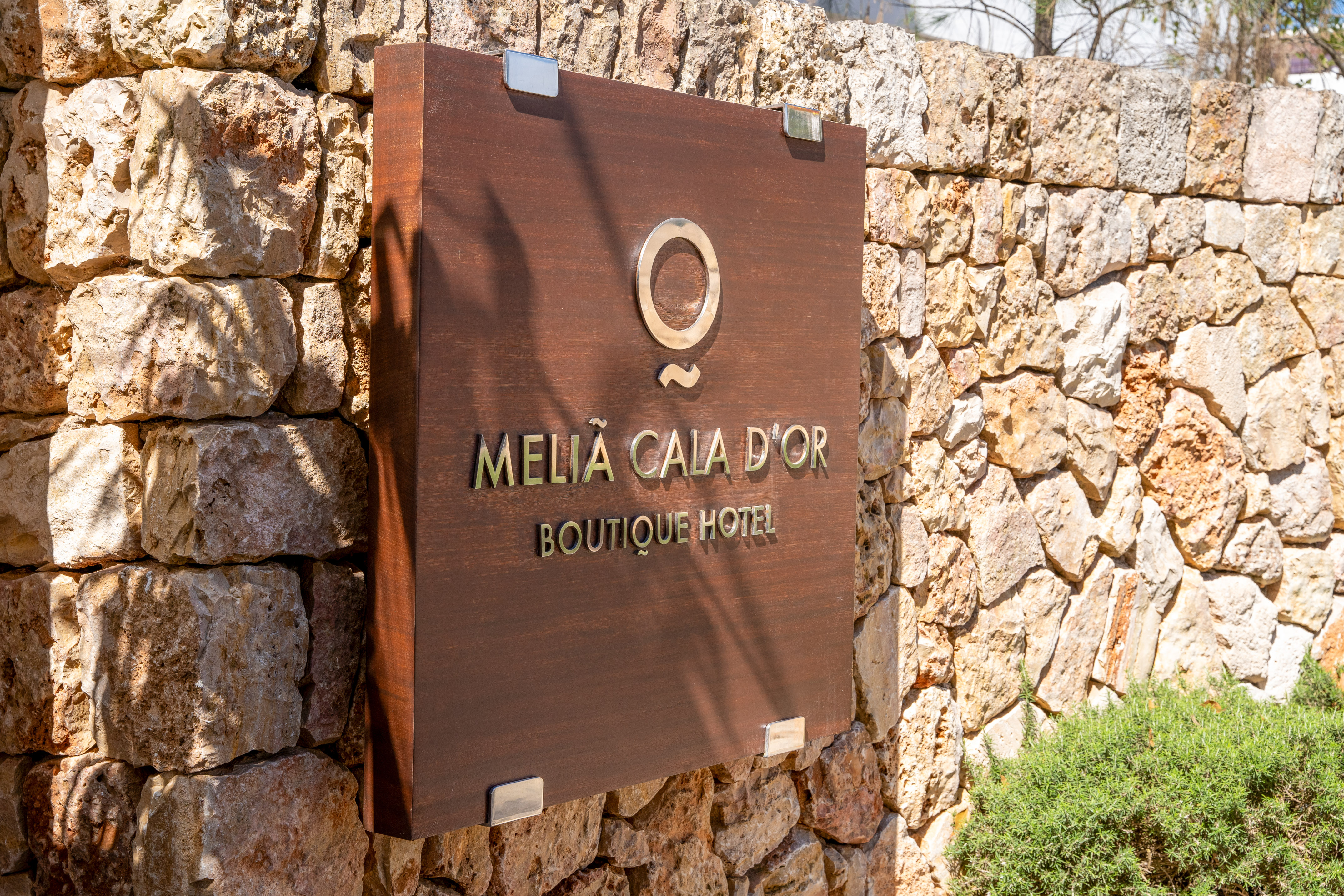 Meliá Cala d'Or Boutique Hotel sign on a rustic stone wall.