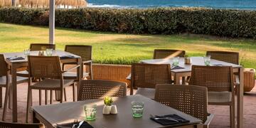 a table and chairs outside with a beach in the background
