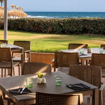a table and chairs outside with a beach in the background