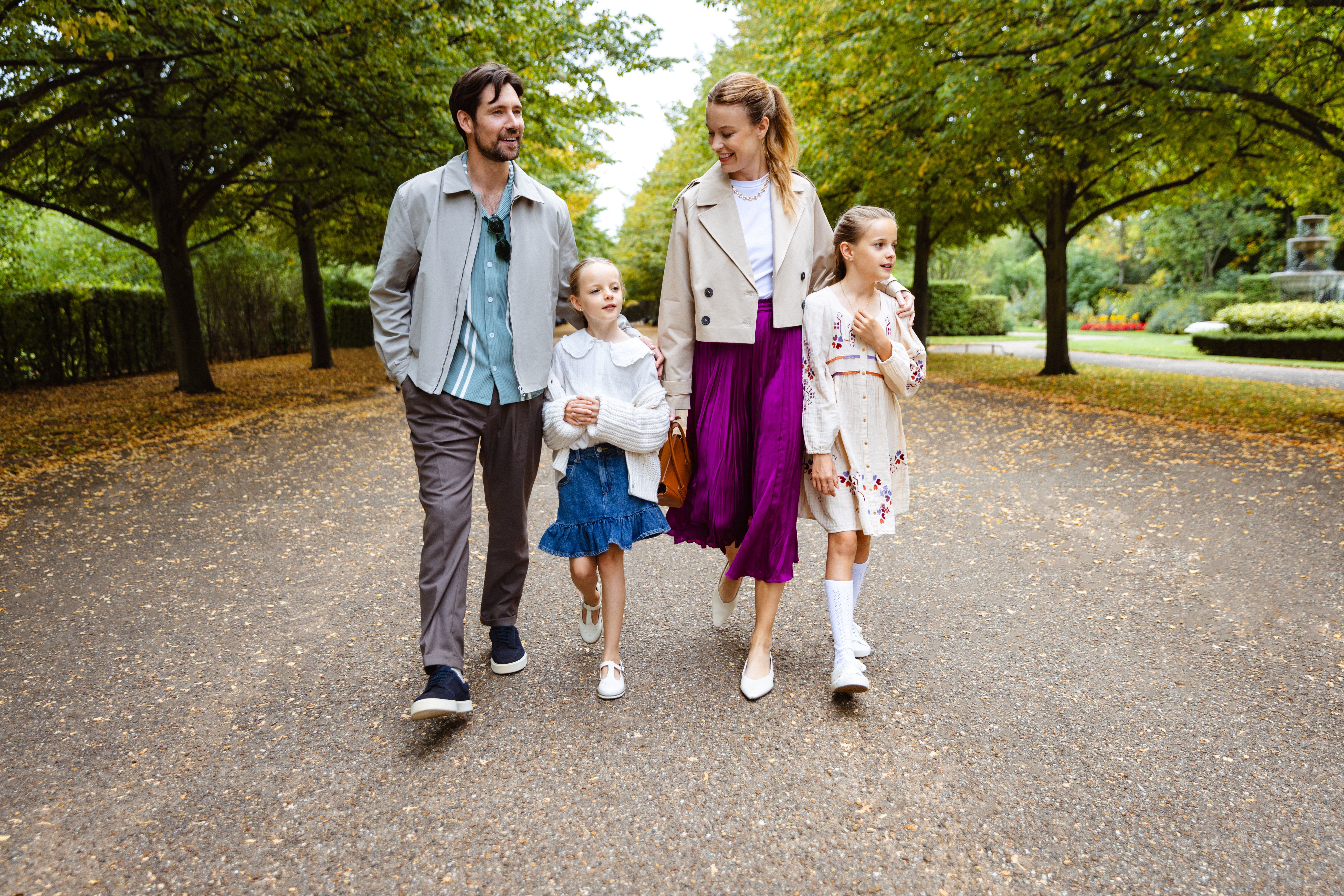 Familia feliz paseando por un sendero arbolado en otoño.