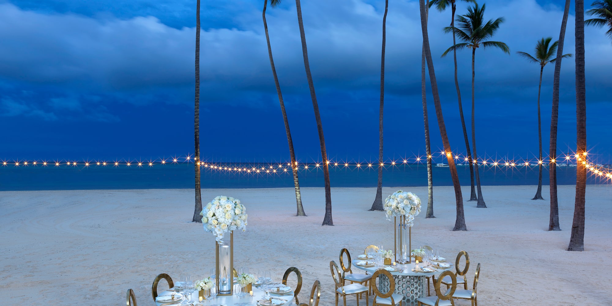 a table set up on a beach with palm trees