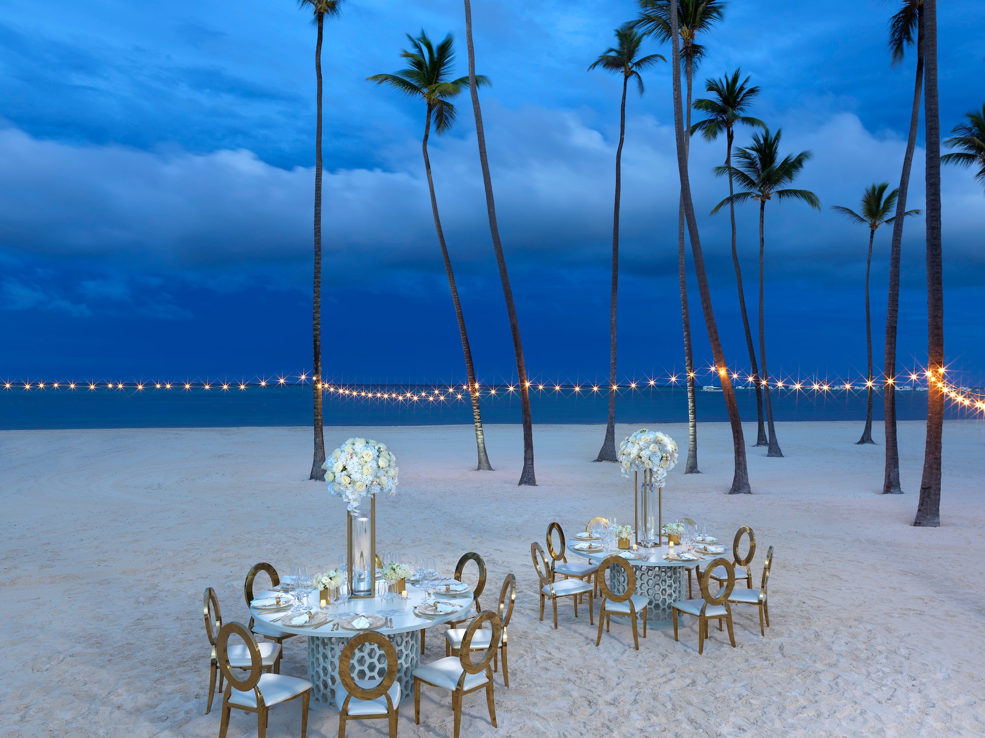 a table set up on a beach with palm trees