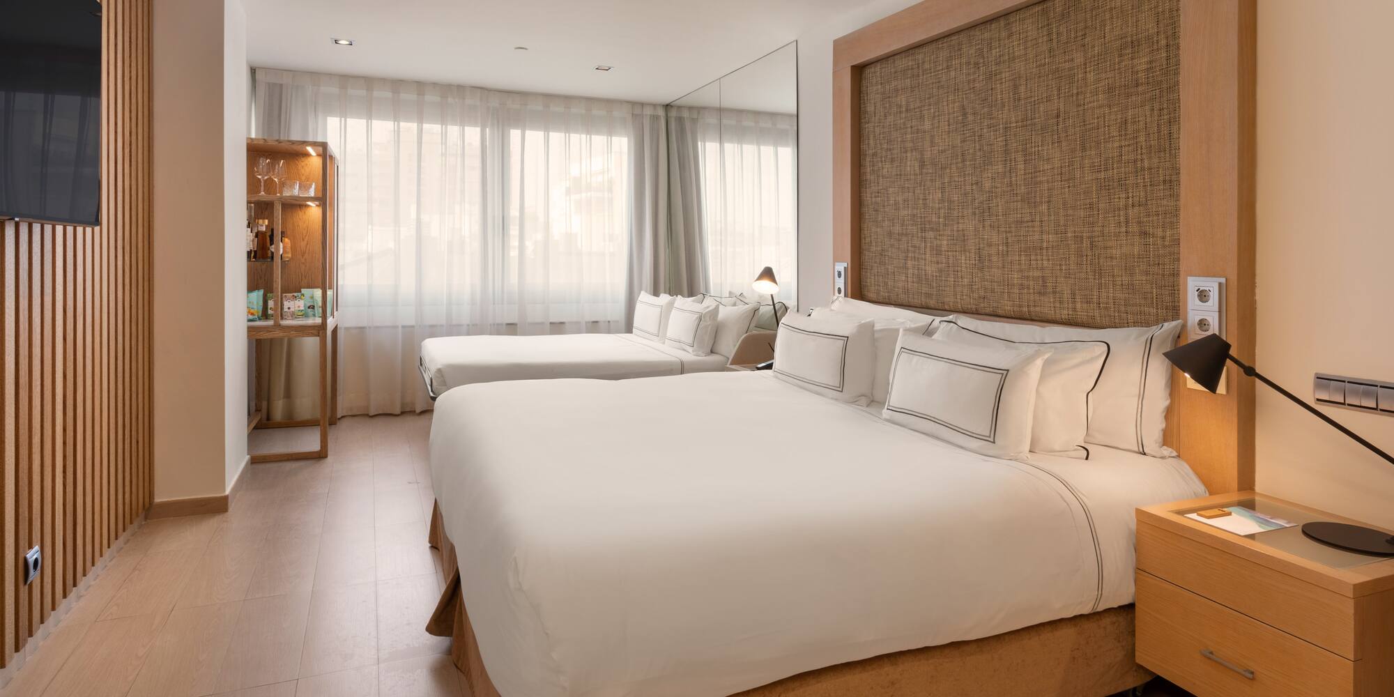 Spacious hotel room with king bed, twin bed, wooden paneling, and modern decor.