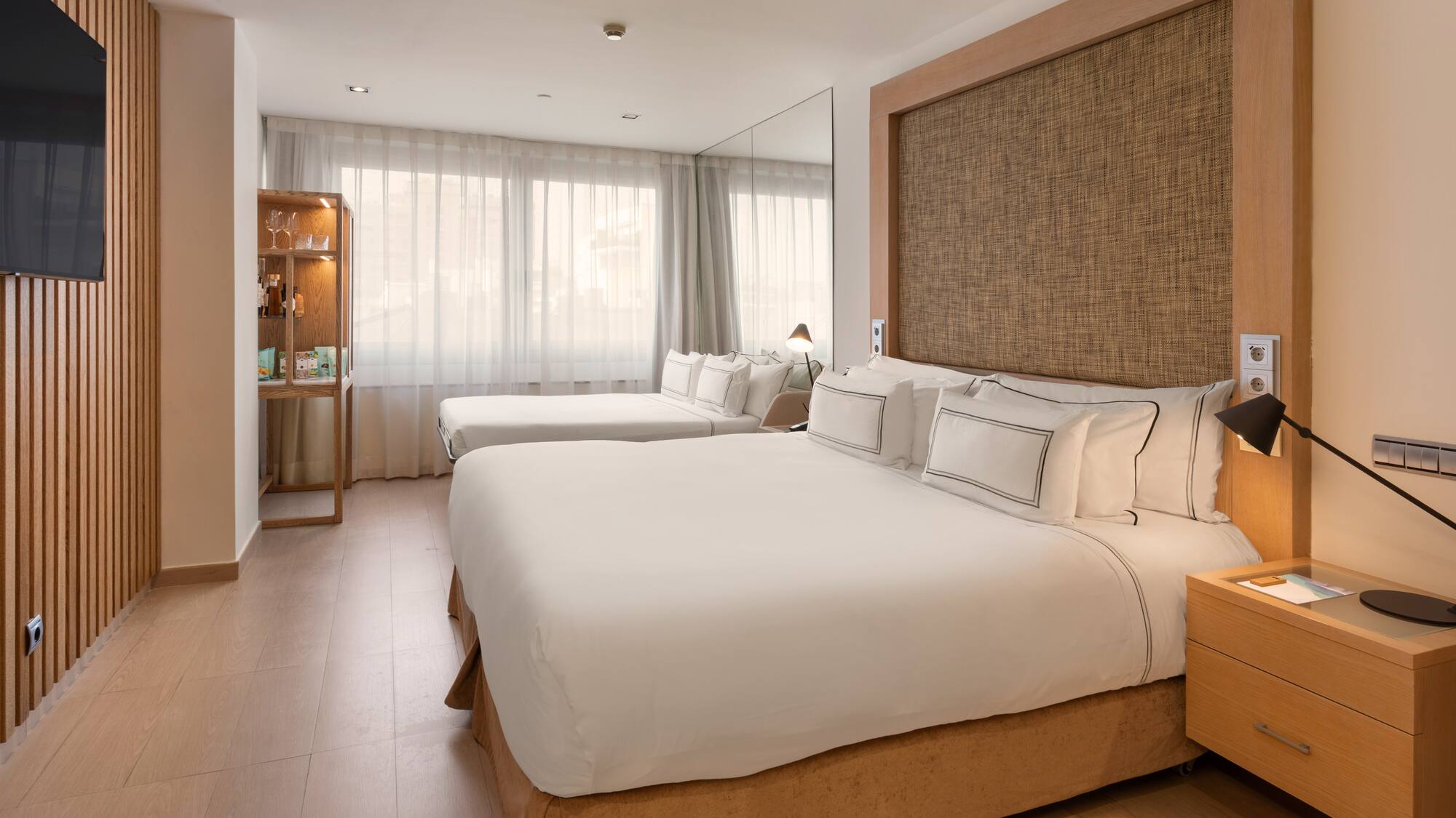 Spacious hotel room with king bed, twin bed, wooden paneling, and modern decor.