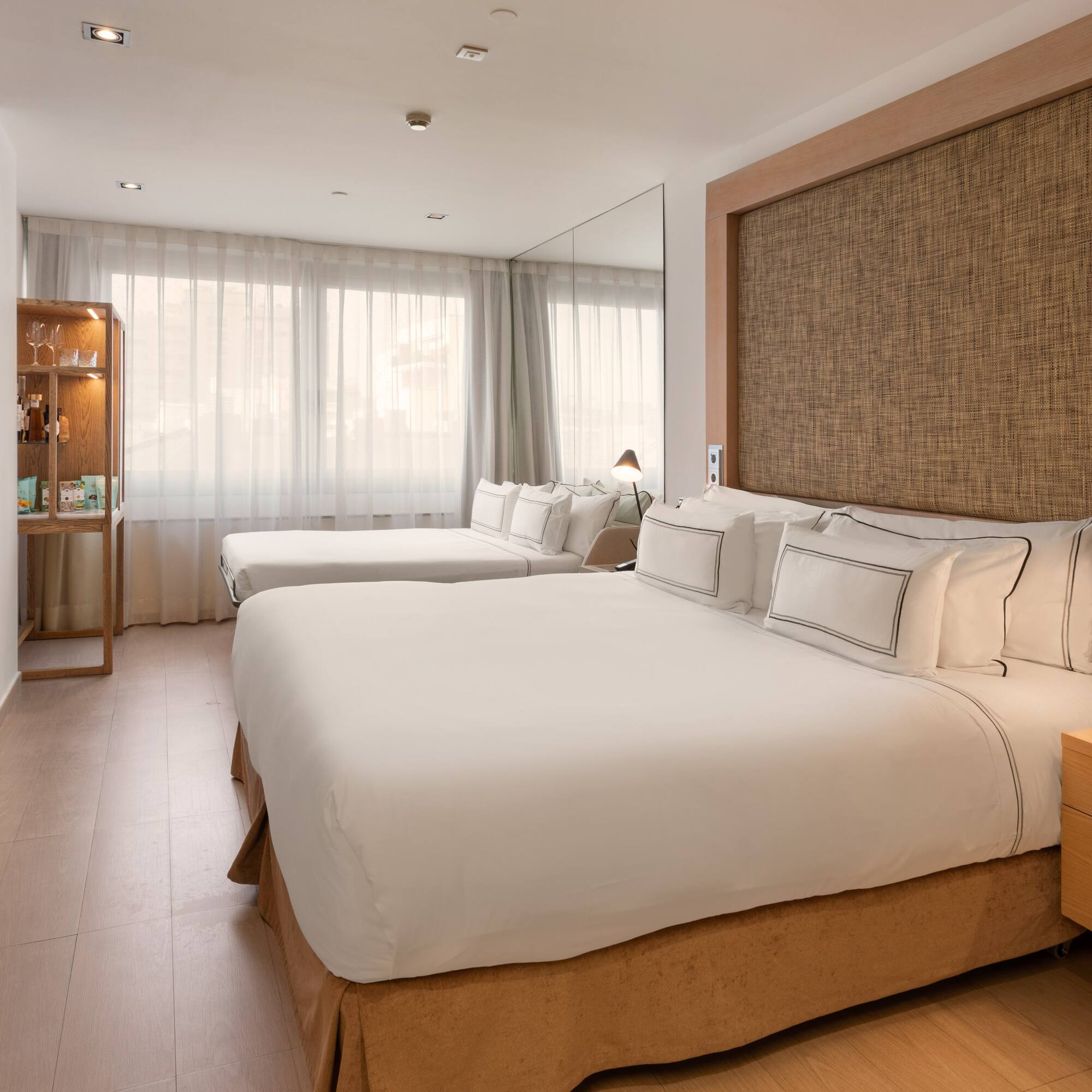 Spacious hotel room with king bed, twin bed, wooden paneling, and modern decor.