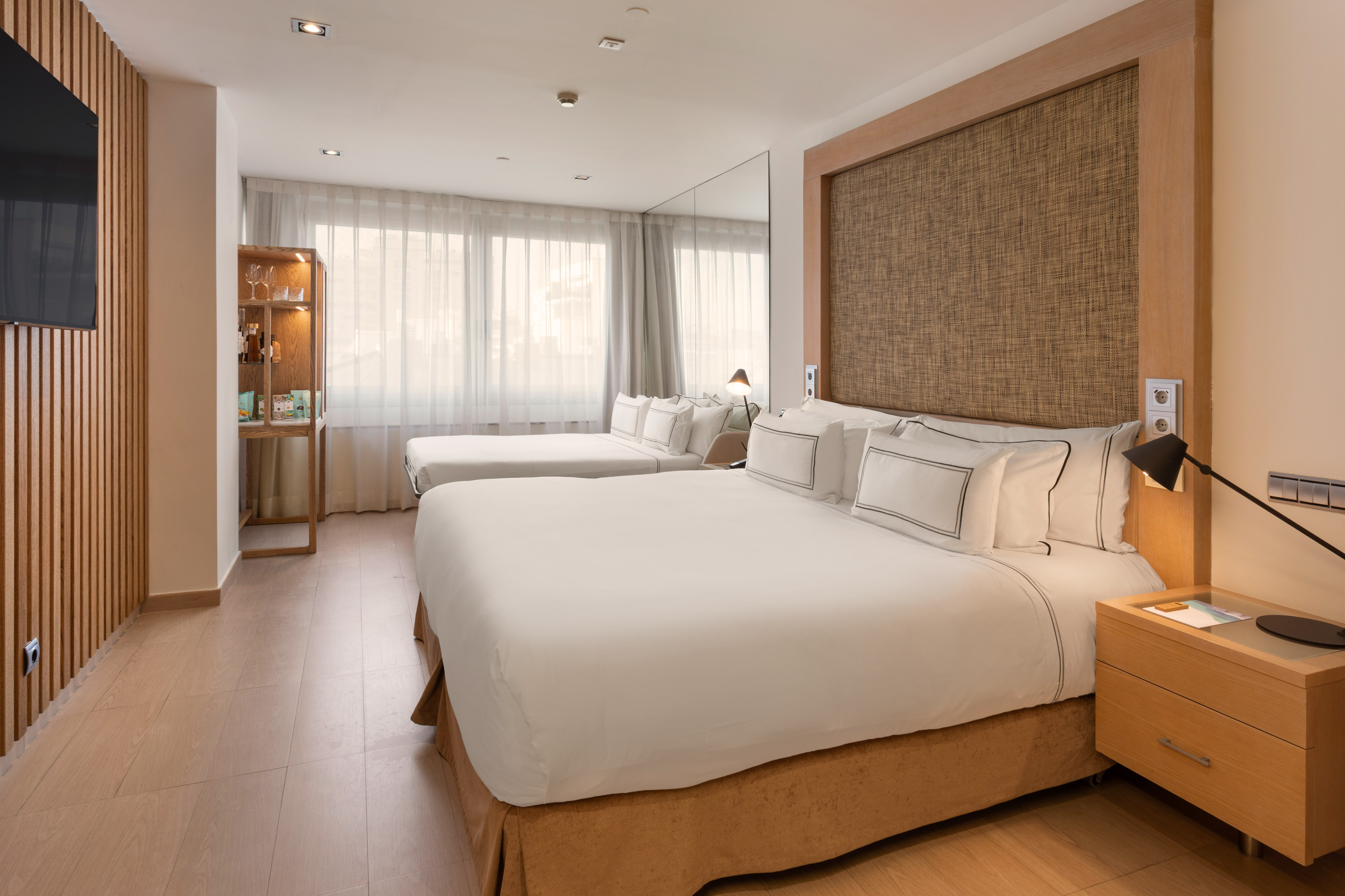 Spacious hotel room with king bed, twin bed, wooden paneling, and modern decor.