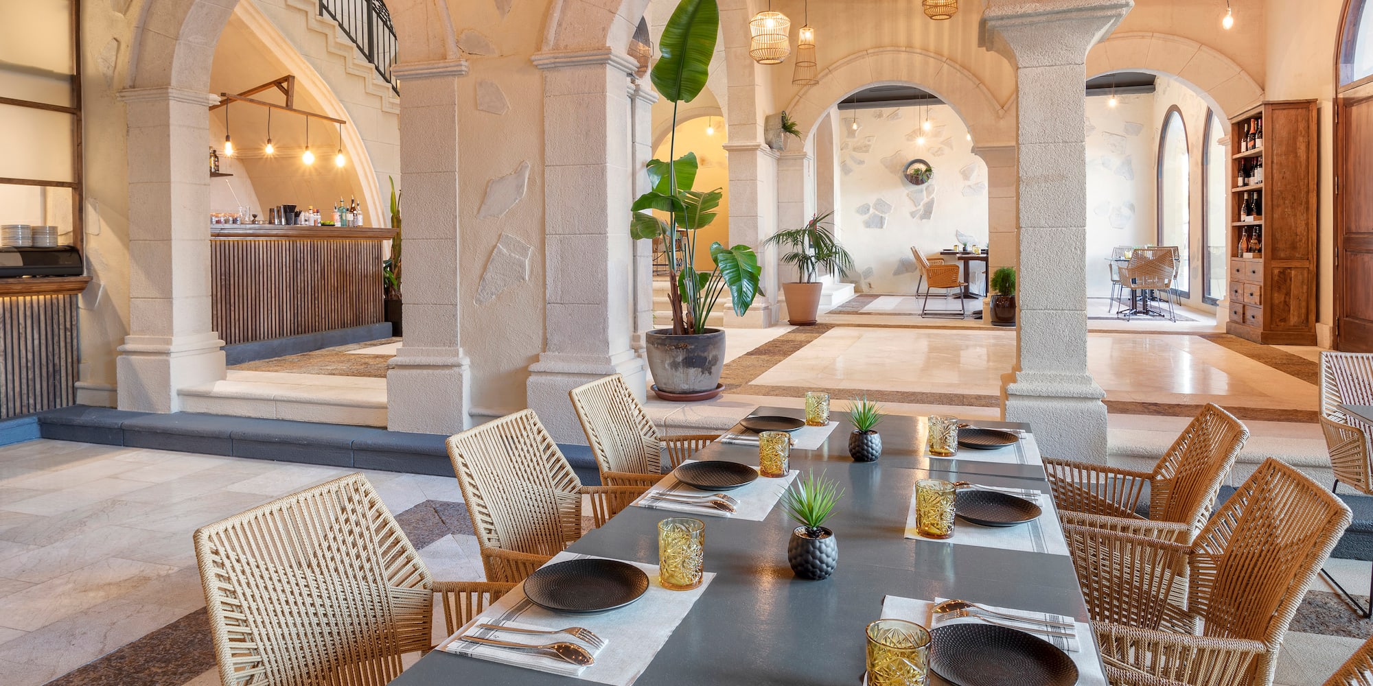 a table with plates and plates on it in a room with stone pillars